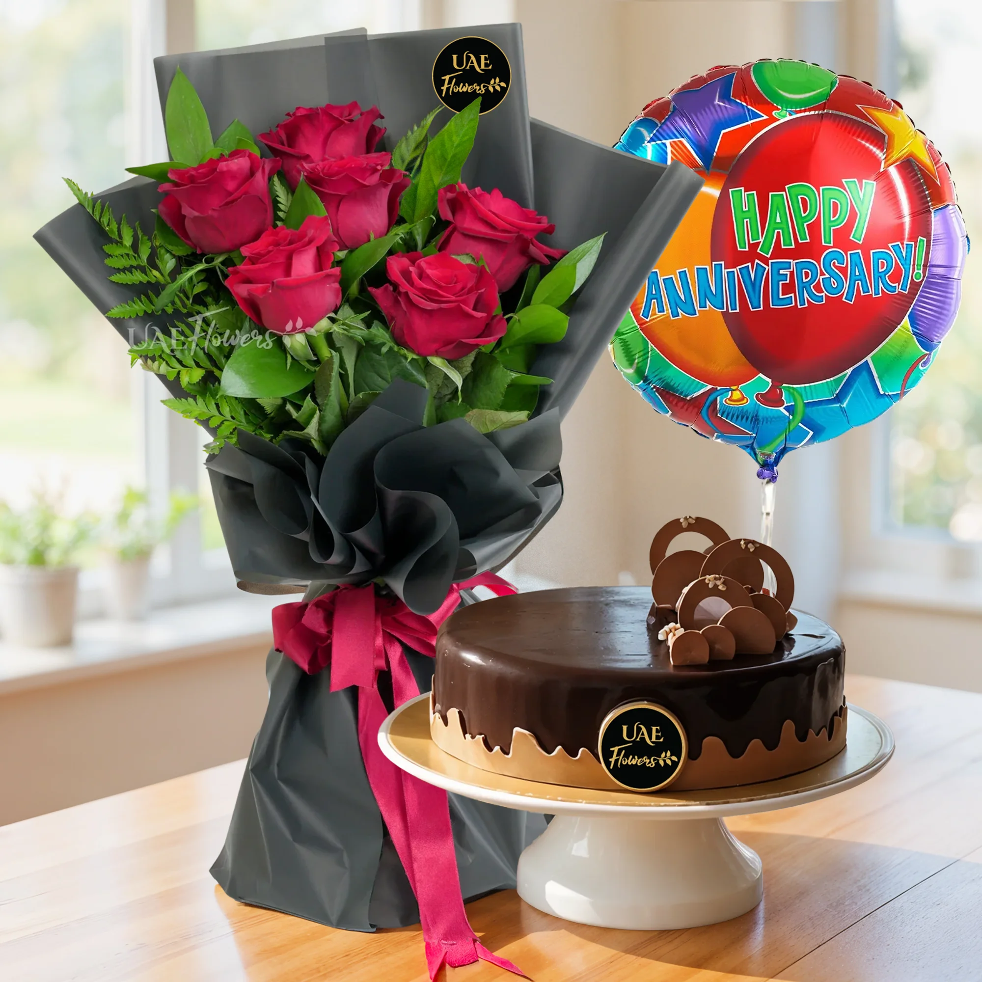 Bouquet of 6 red roses with green fillers in black wrapping, 1 kg chocolate cake and HAPPY ANNIVERSARY foil balloon.