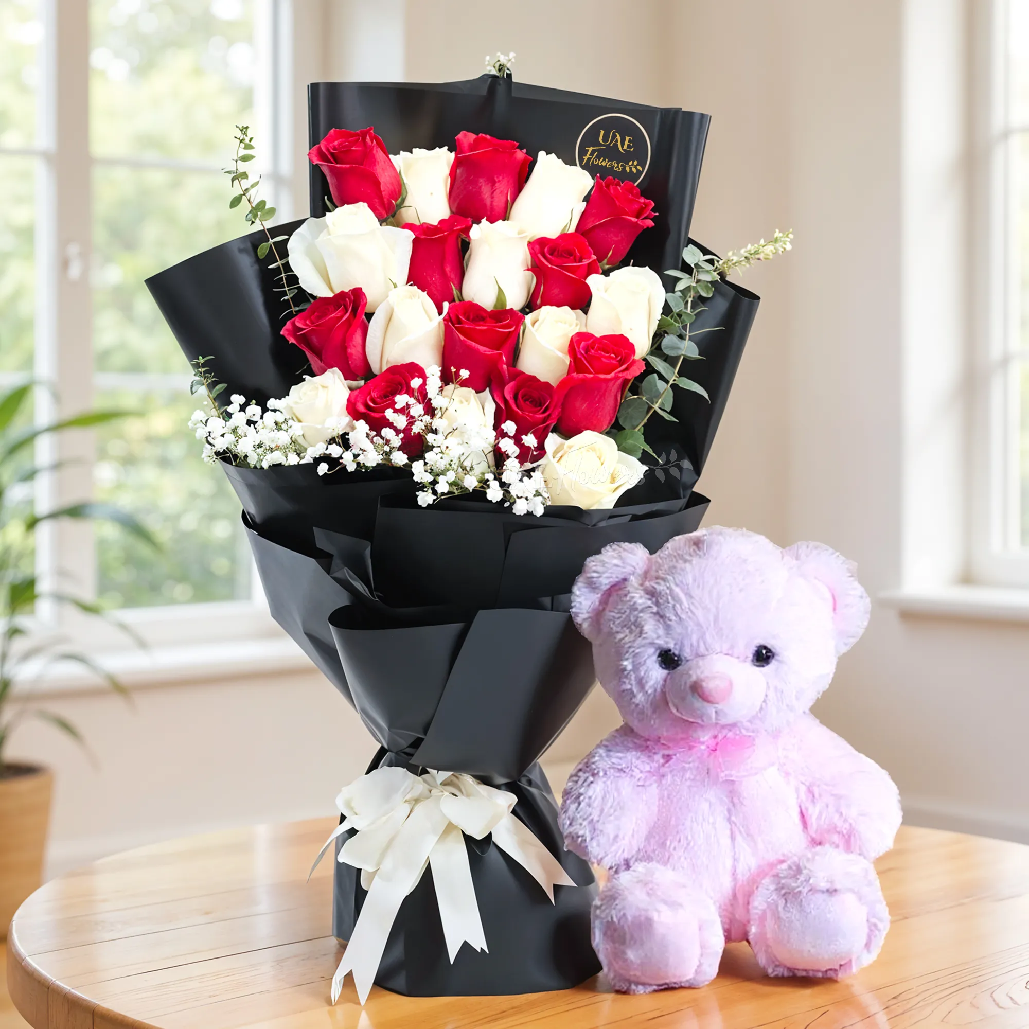 Bouquet of 10 red and 10 white roses with baby's breath fillers in black wrapping and a small pink teddy bear.