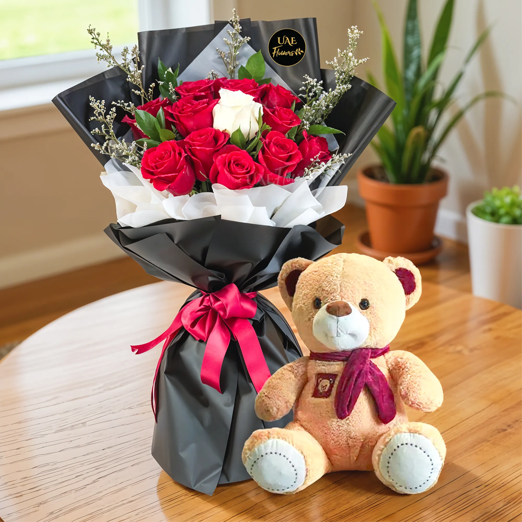 Bouquet of 11 red roses and 1 white rose in center with greens in nice wrapping and a small brown teddy bear.