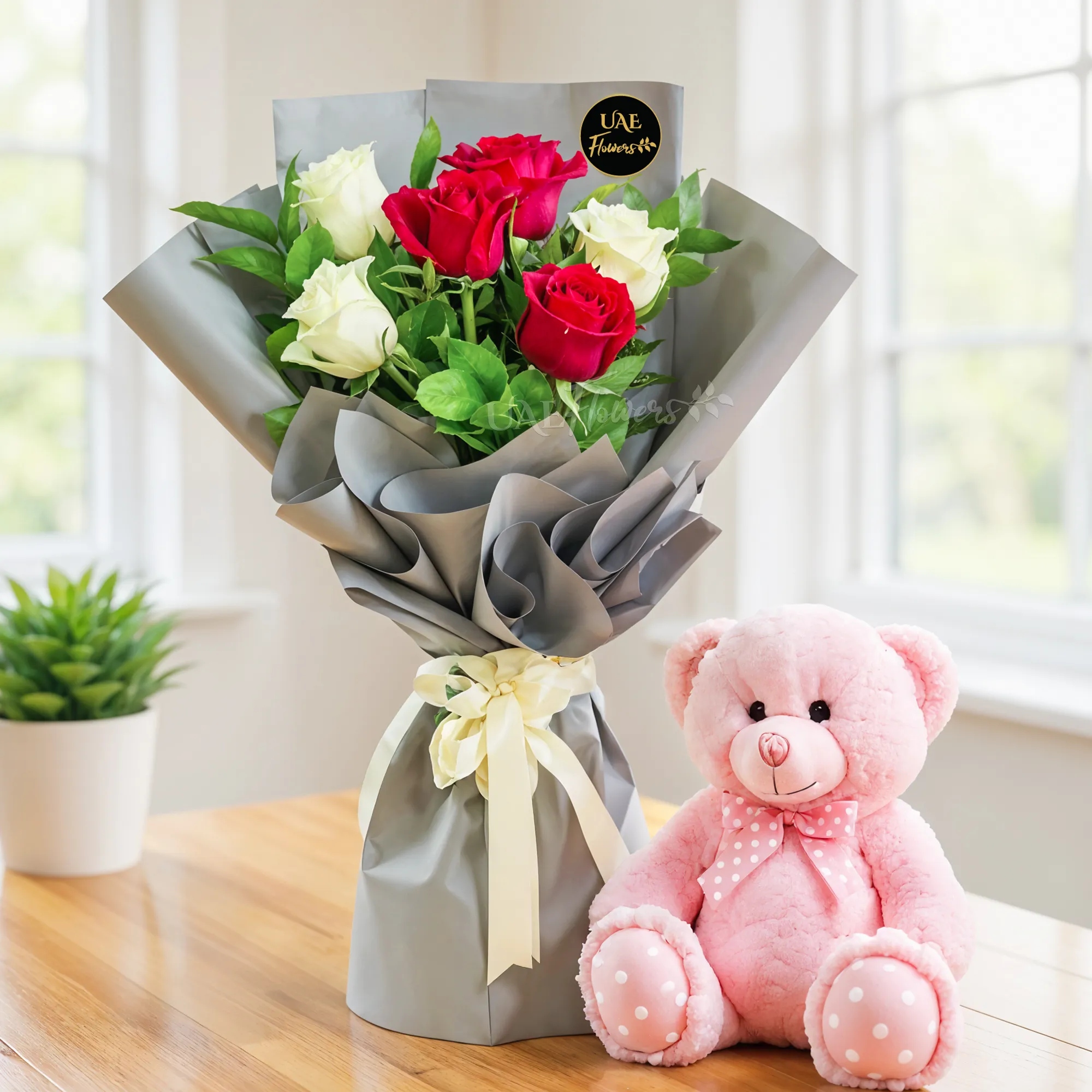 Bouquet of 3 red and 3 white roses with green fillers in nice wrapping and a small pink teddy bear.