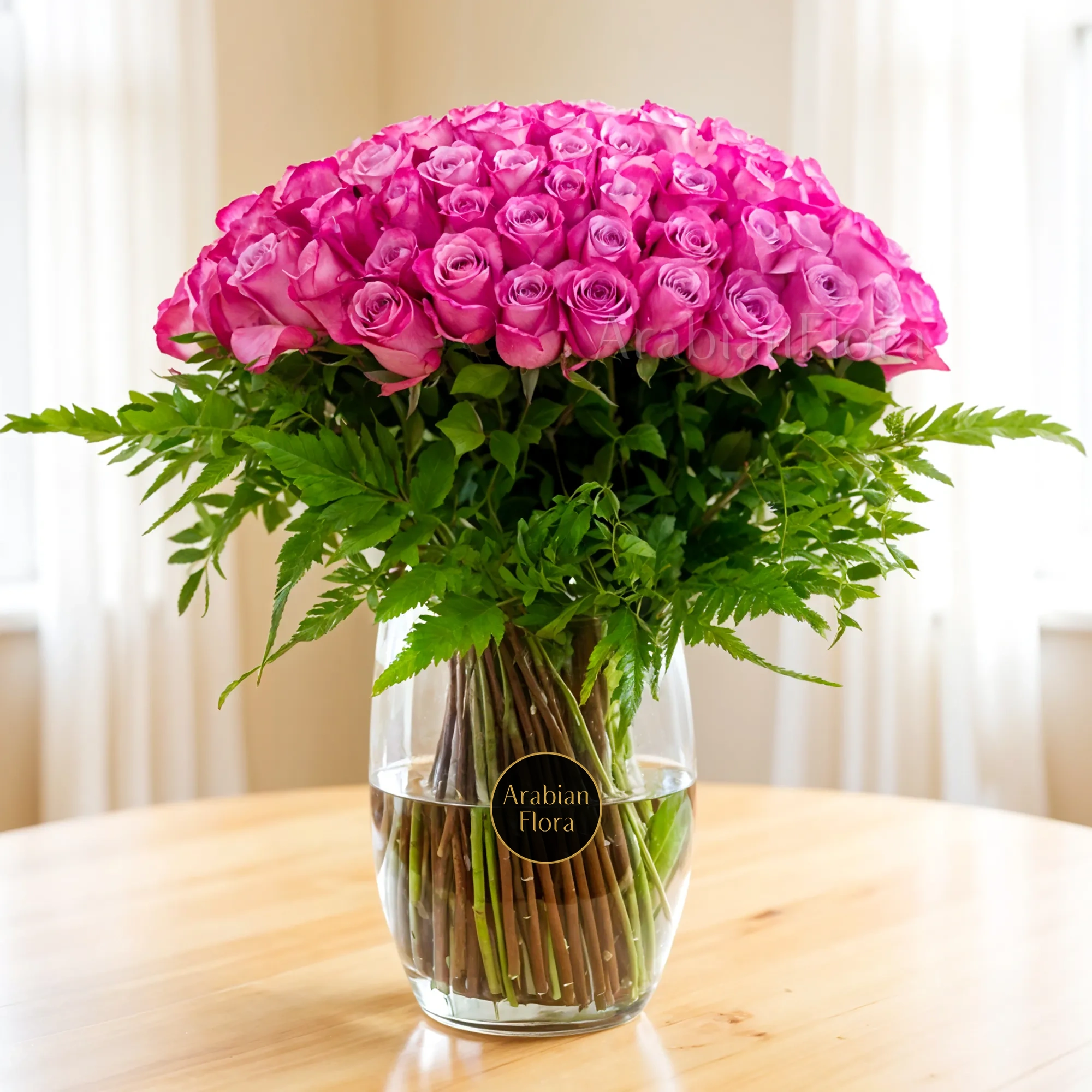 100 Purple Roses with green fillers in a glass vase.