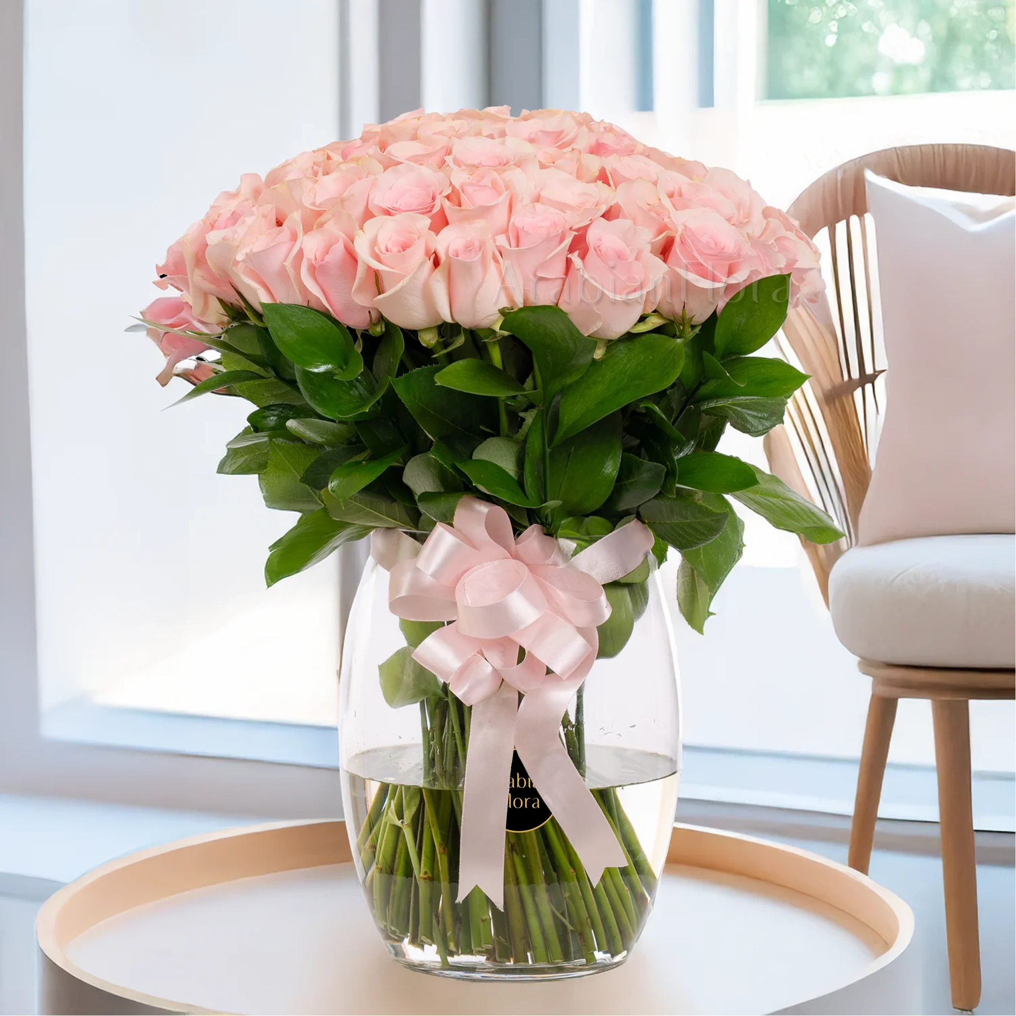 A glass vase arrangement of 50 pink roses with  with pink ribbons.