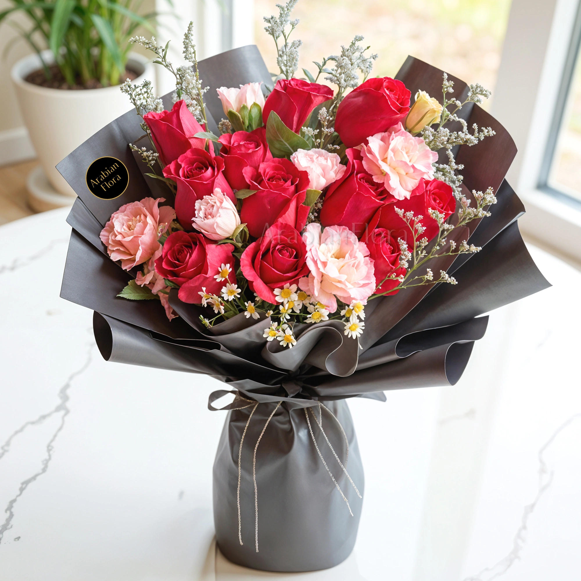 Bouquet of 12 stems of red roses and 6 stems of pink carnations with fillers in black wrapping.