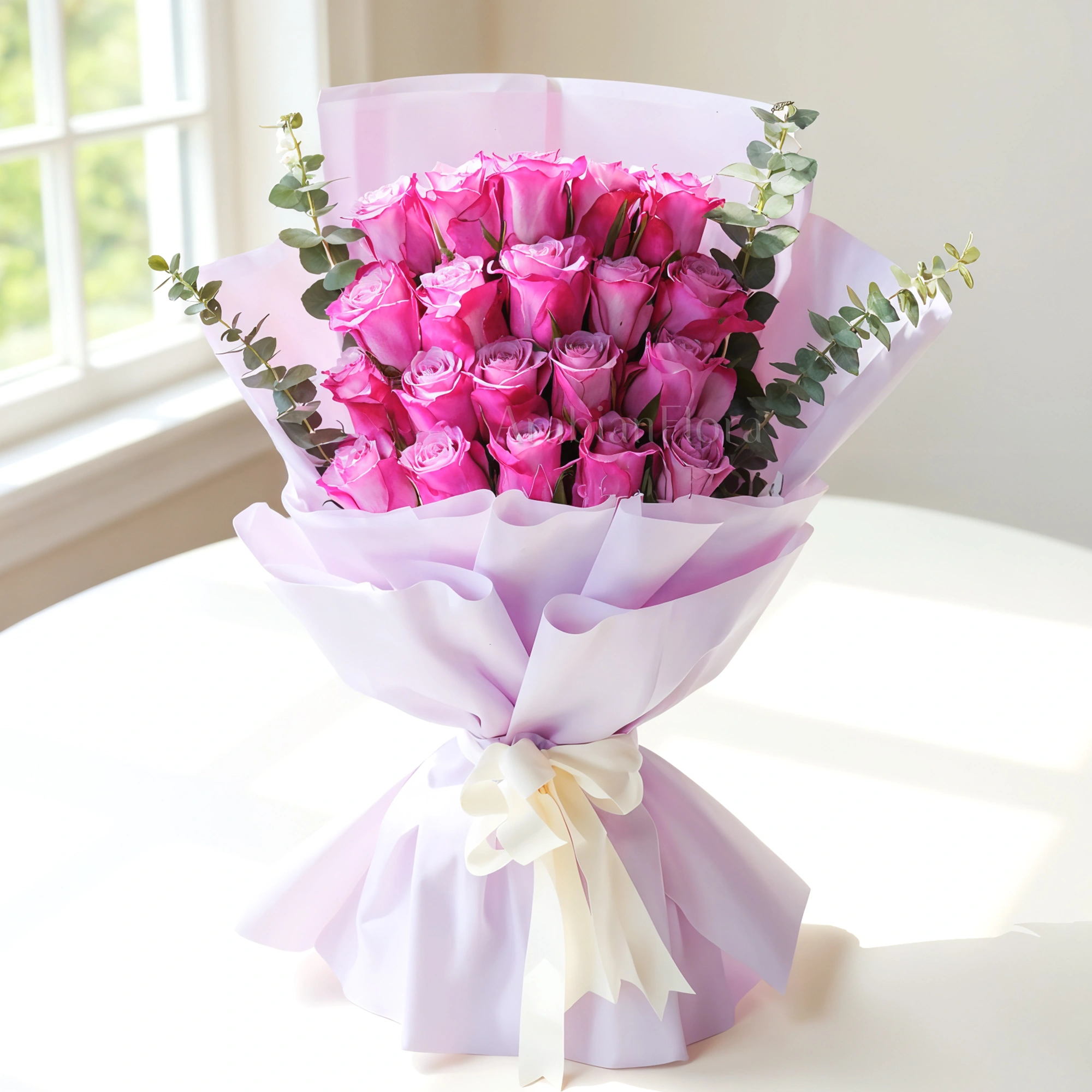 Bouquet of 20 purple roses with eucalyptus leaf in pink paper packing tied with white ribbons.