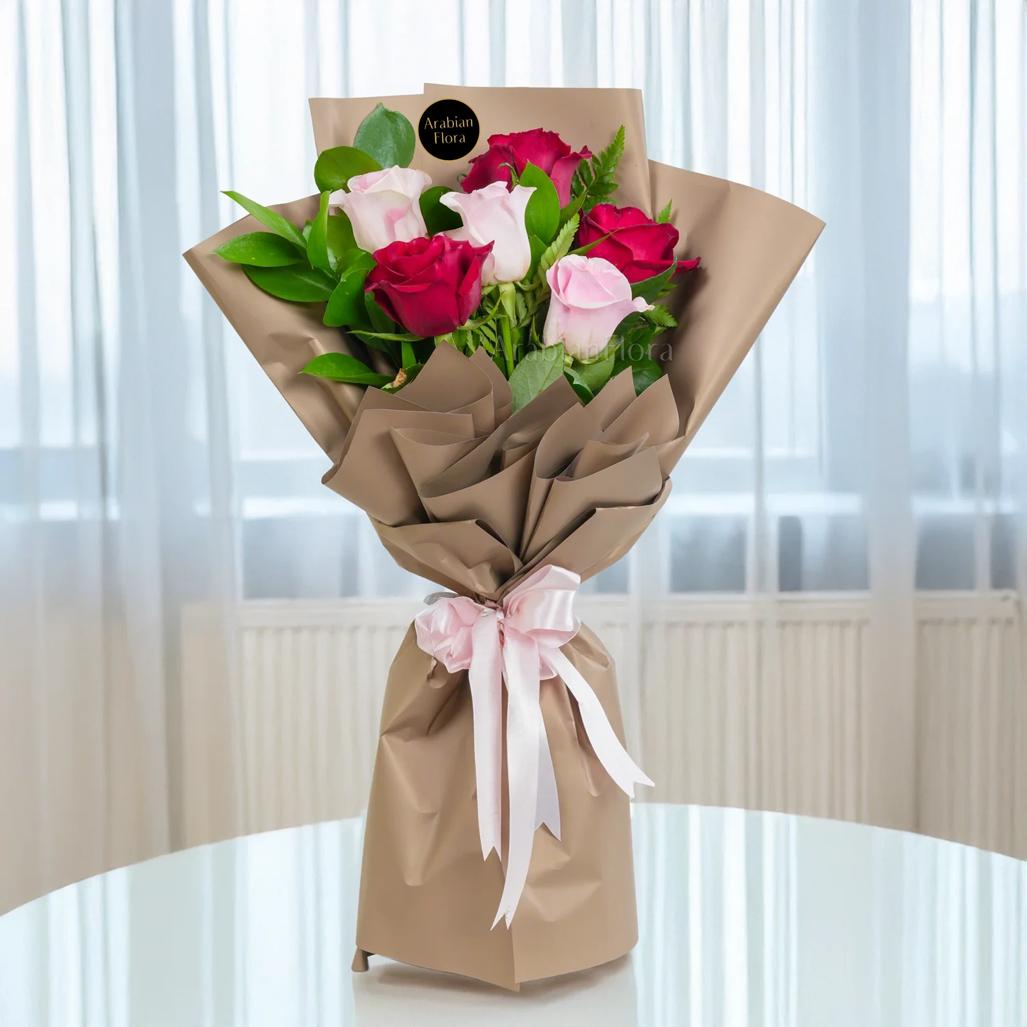 Bouquet of 6 red & pink roses with green fillers in paper packing tied with ribbons.
