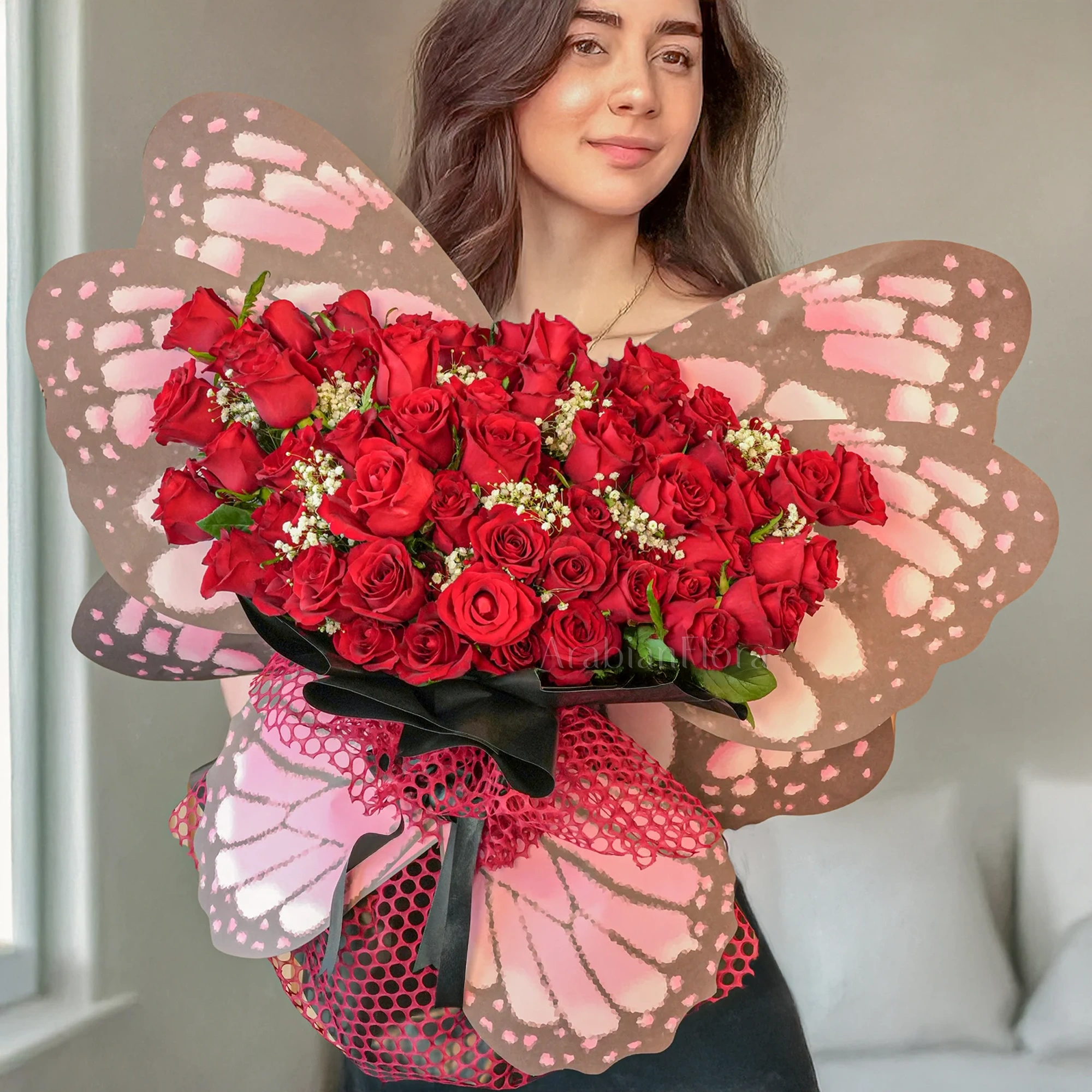 Butterfly bouquet of 50 Red Roses with baby's breath & green fillers tied with ribbons.