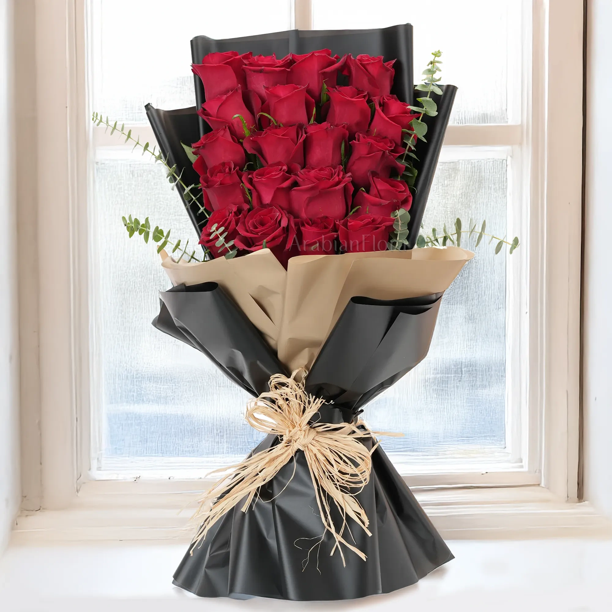 Bouquet of 20 red roses with green fillers in paper packing.