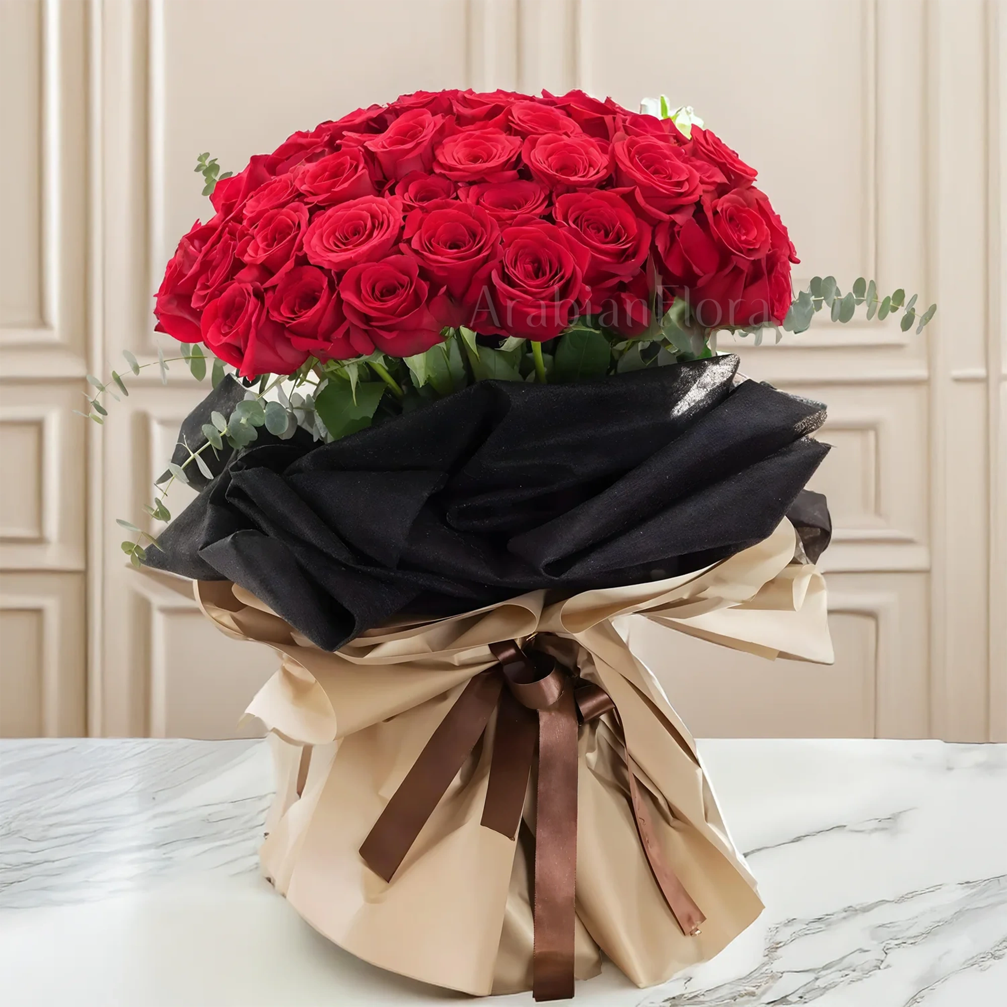 Bouquet of 40 red roses with eucalyptus leaf in black and brown paper packing tied with brown ribbons.