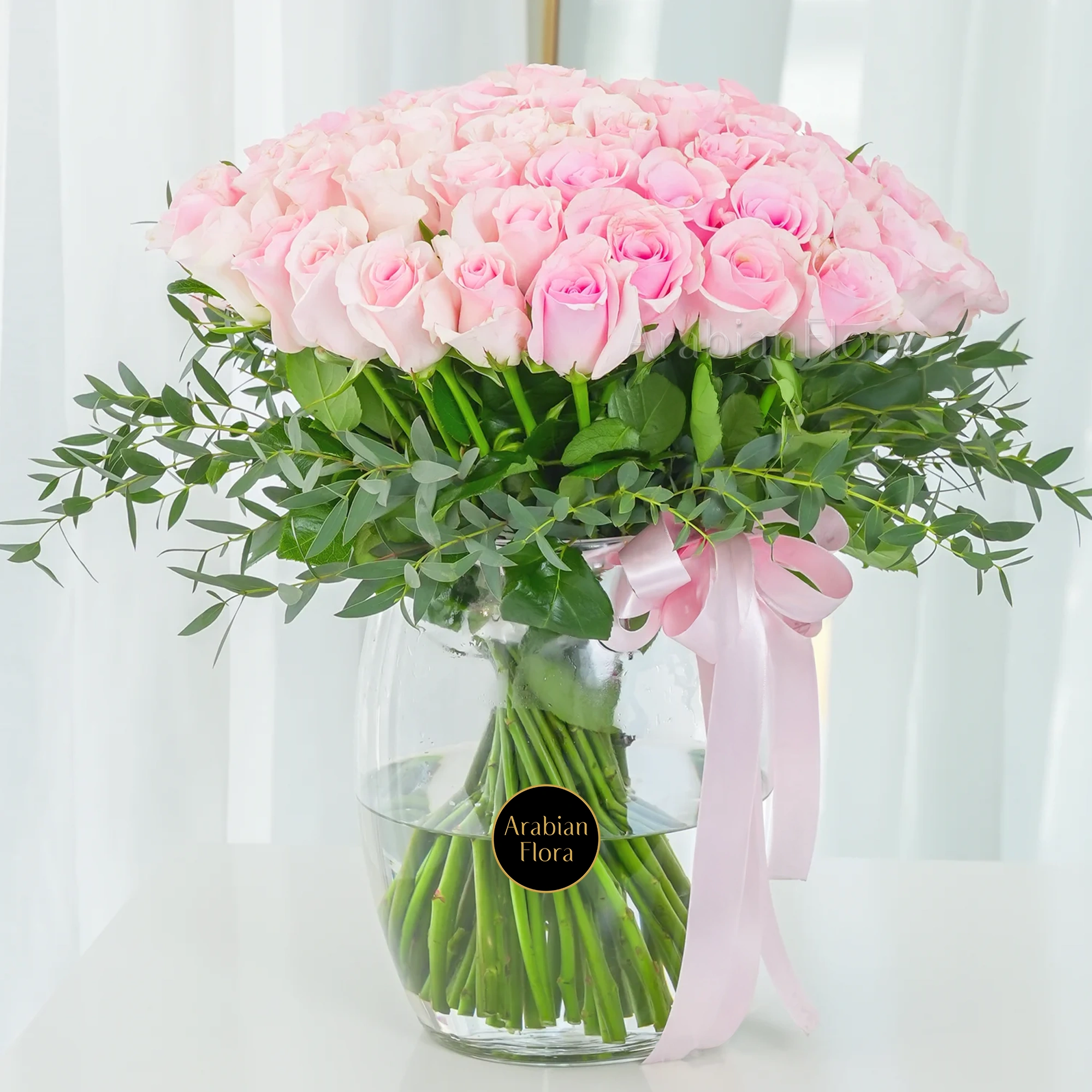 A vase arrangement of 40 pink roses with green fillers and tied with pink ribbons.