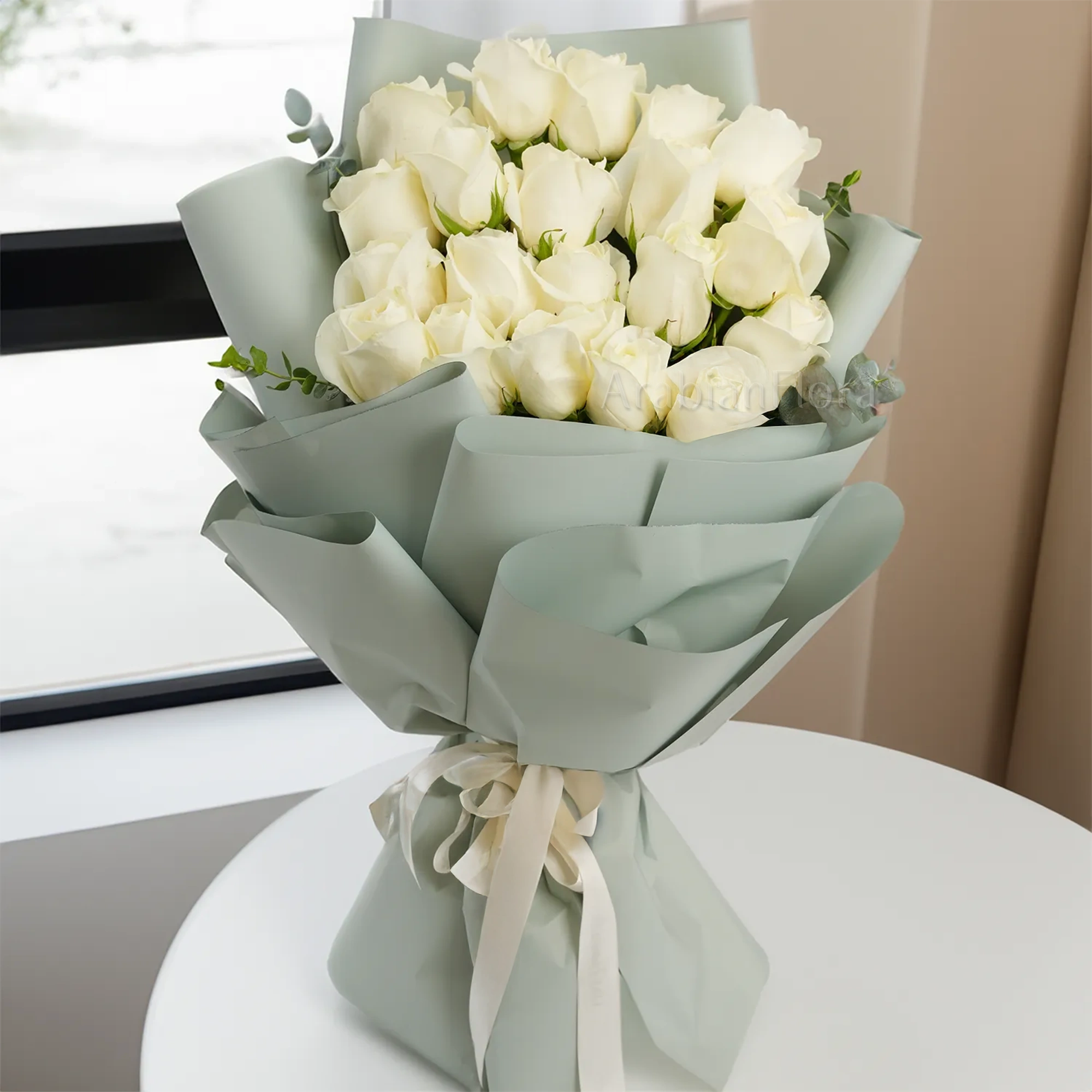 Bouquet of 20 white roses with green fillers in paper packing tied with white ribbons