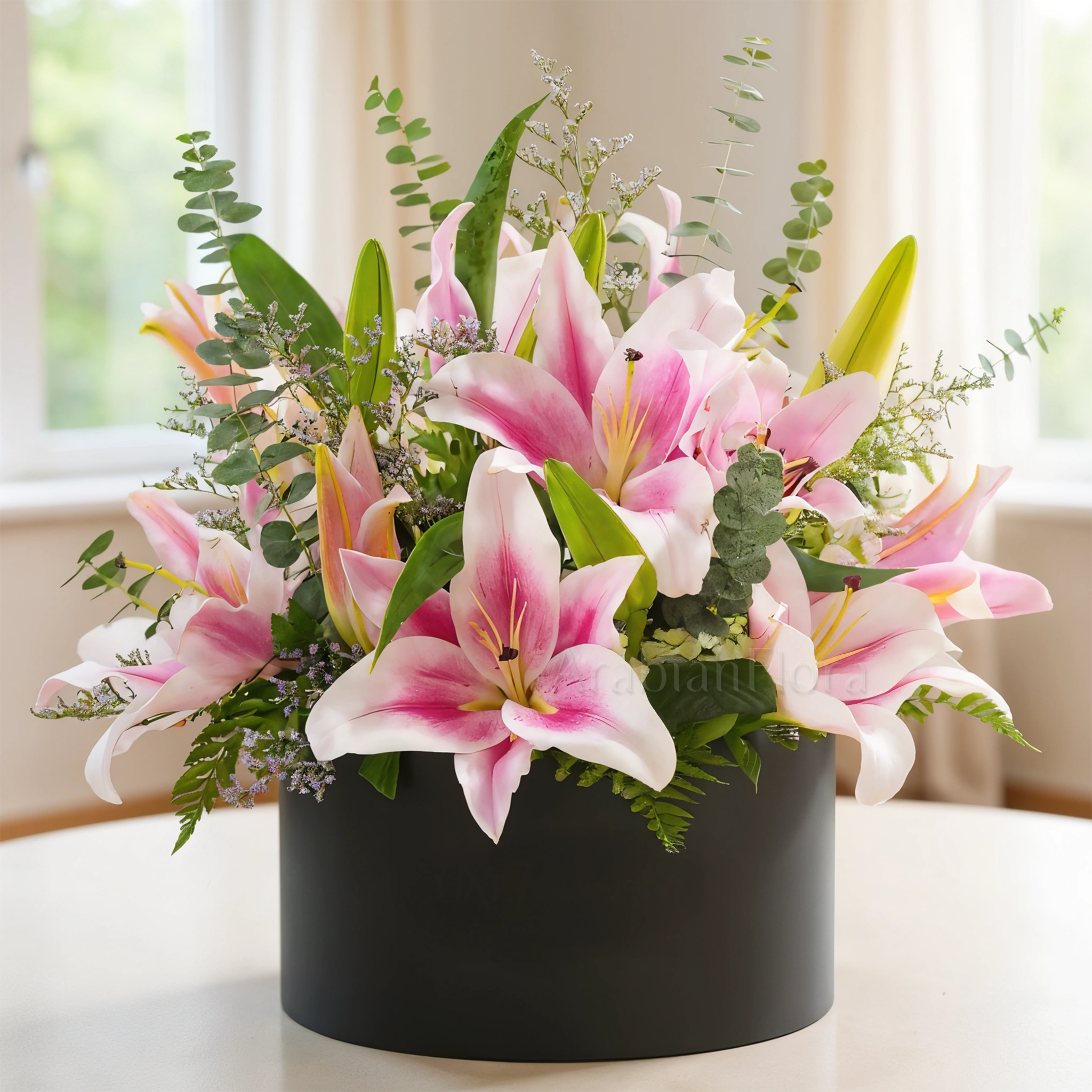 5 pink lilies with eucalyptus leaf and limonium fillers in a black box.