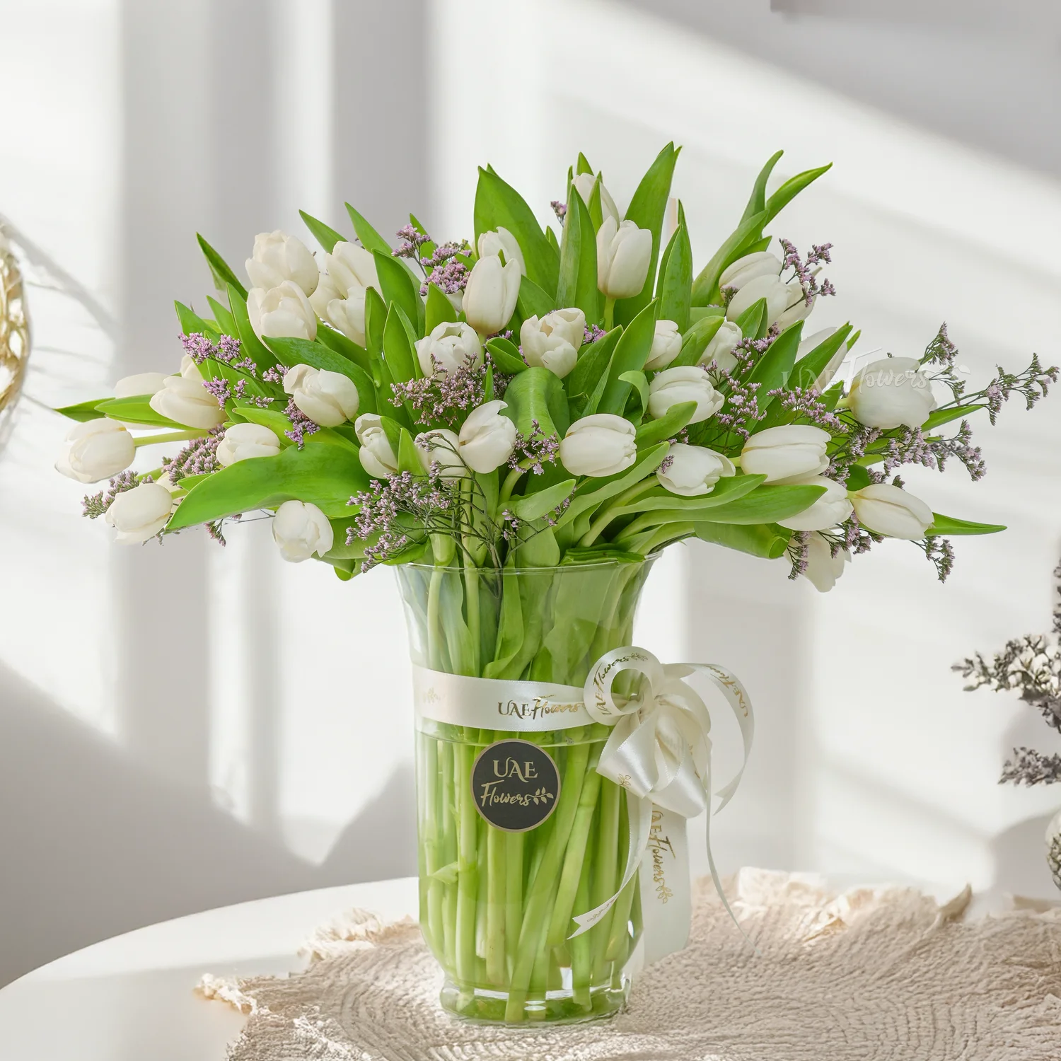 40 white tulips vase arrangement with limonium fillers & a white ribbon.