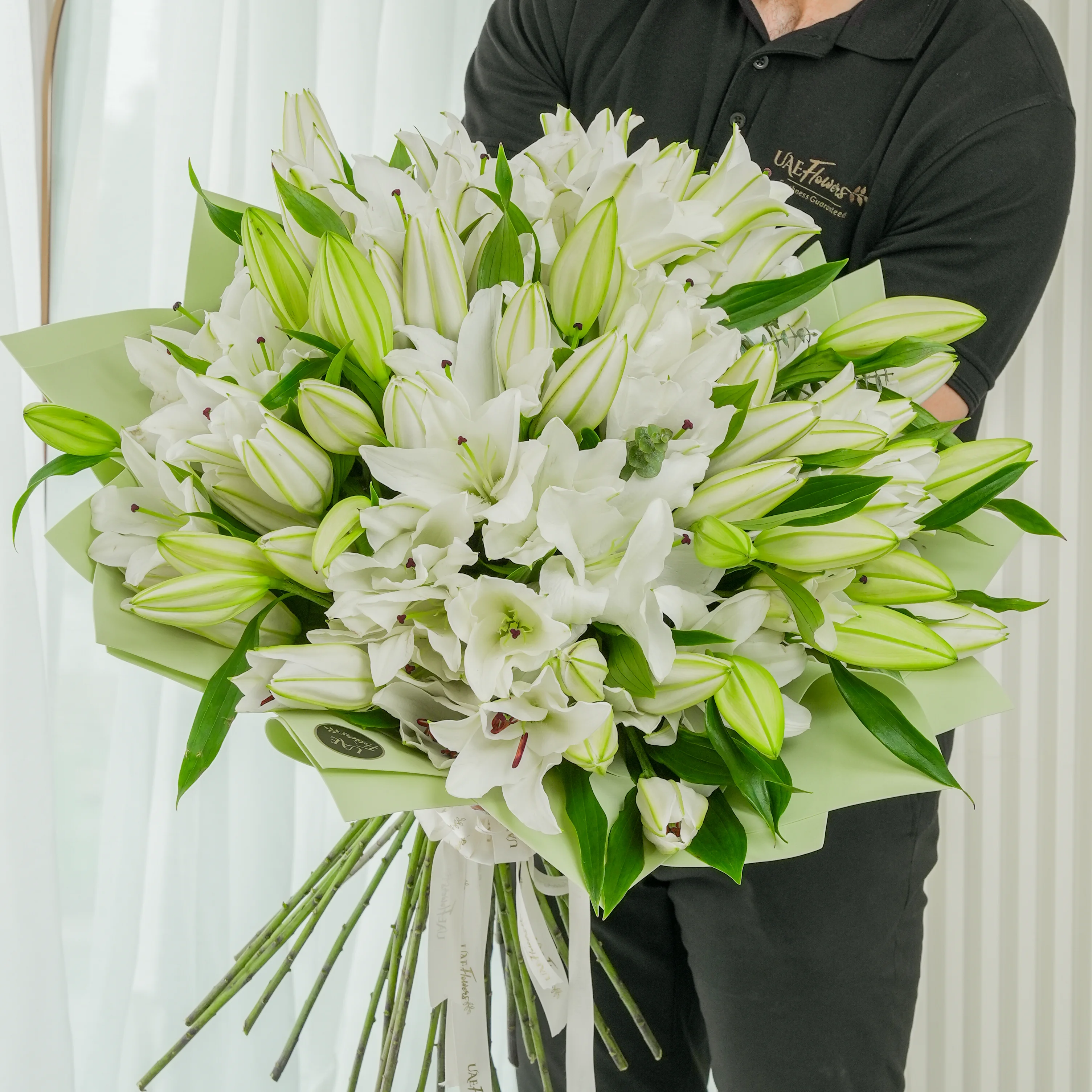 Bouquet of 20 white lilies with green fillers beautifully wrapped in pastel green wrapping paper.