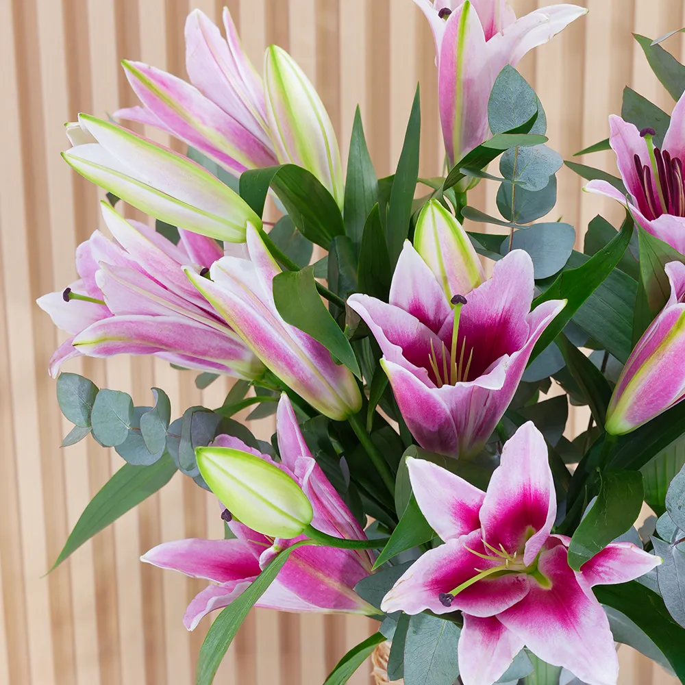 5 pink lilies with green fillers in a glass vase