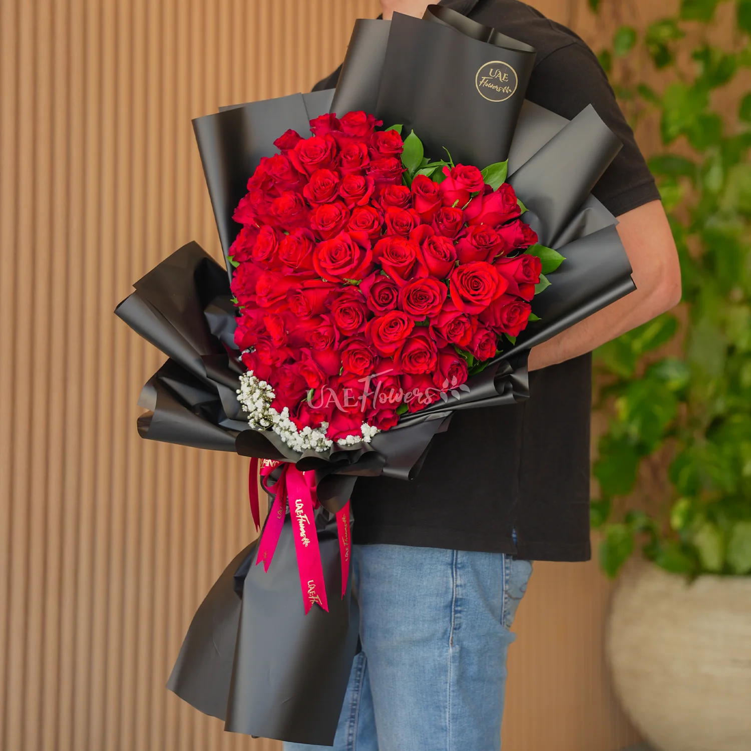 Bouquet of 50 red roses heart-shaped with baby's breath fillers in paper packing and tied with red ribbons.