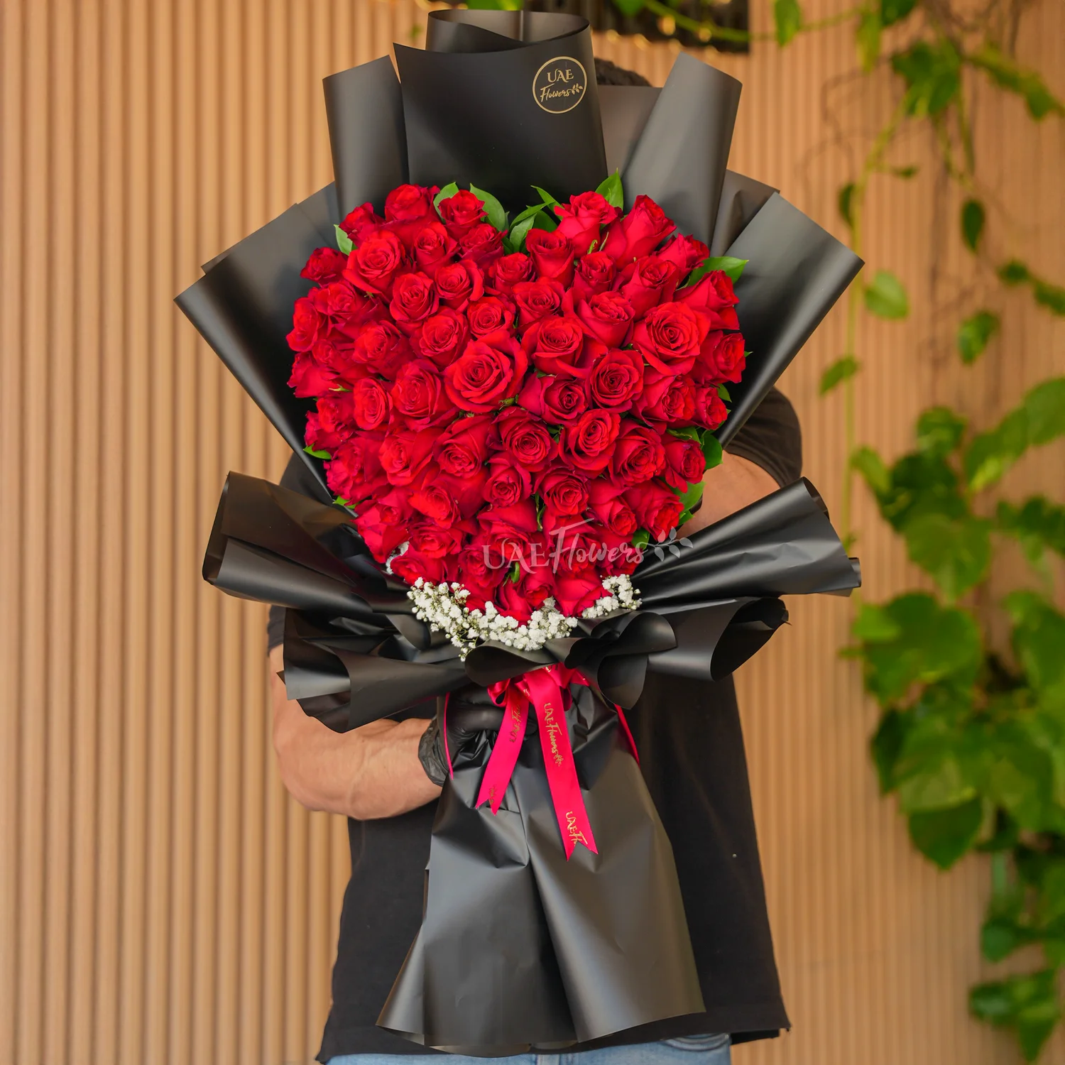 Bouquet of 50 red roses heart-shaped with baby's breath fillers in paper packing and tied with red ribbons.