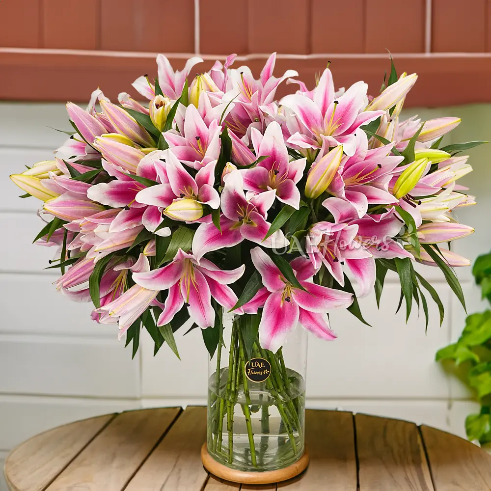 20 stems of pink lilies with eucalyptus leaf and green fillers in a glass vase.