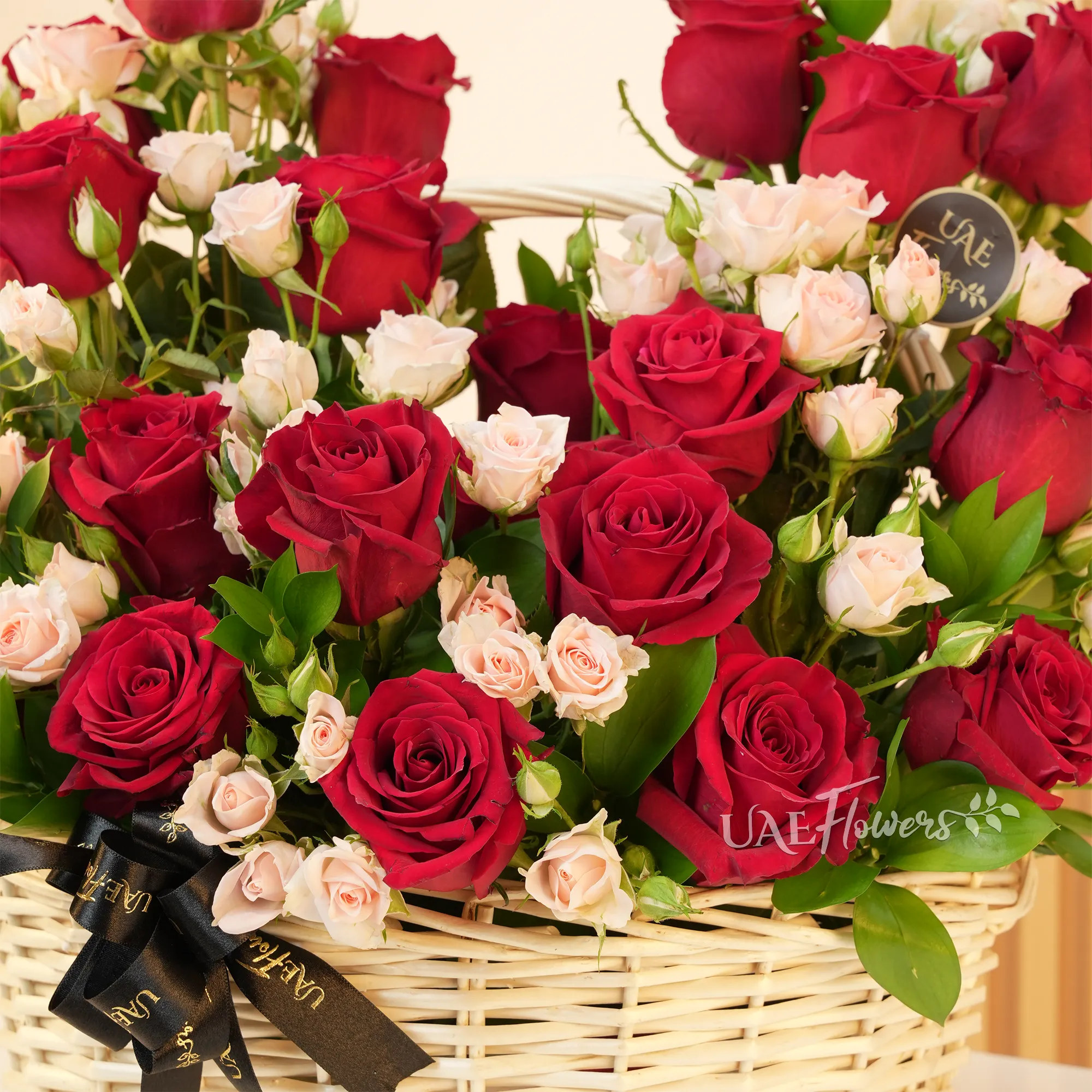 An arrangement of 20 red roses and 6 pink spray roses with green fillers in a handle basket.