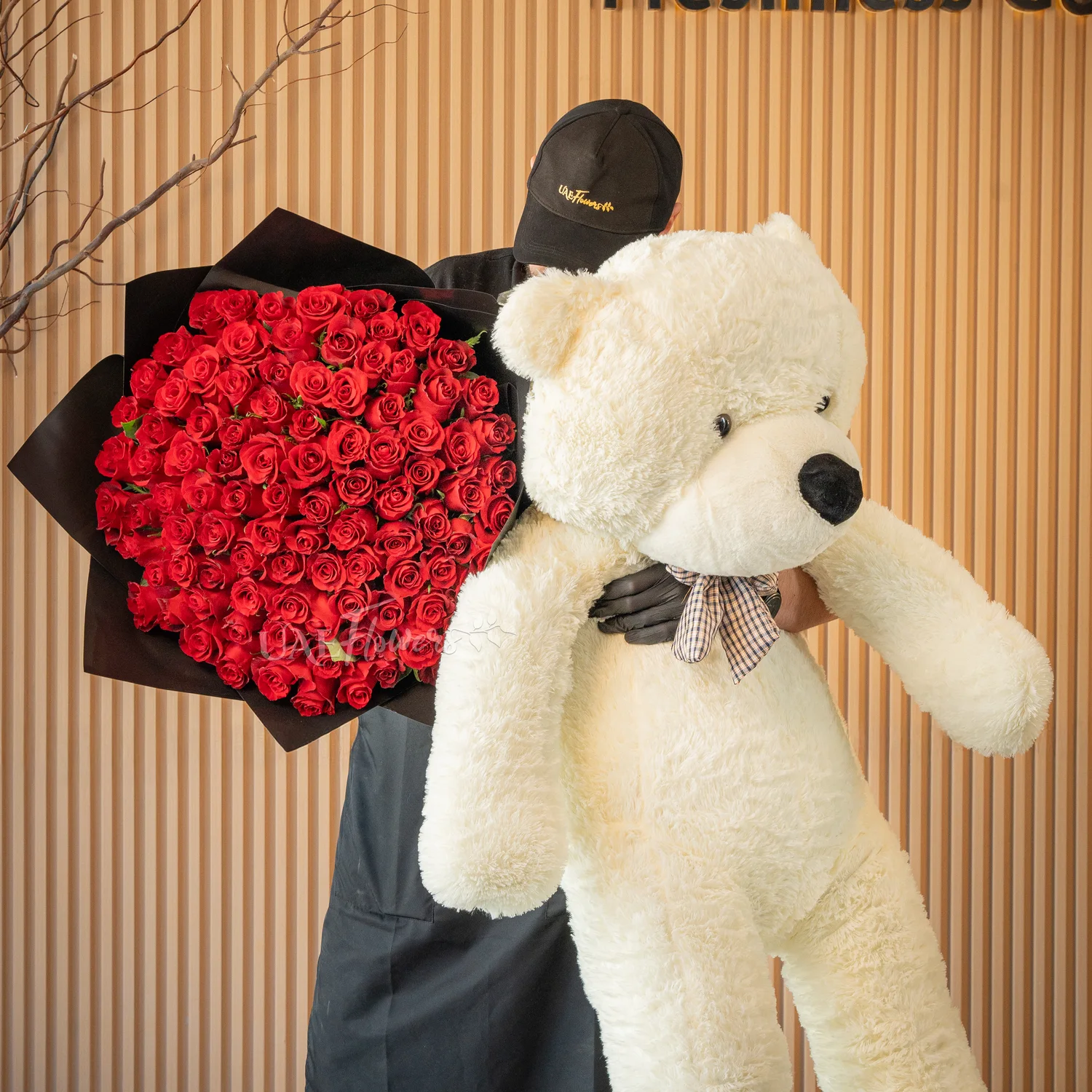 Bouquet of 100 red roses in black paper packing and jumbo white teddy bear.