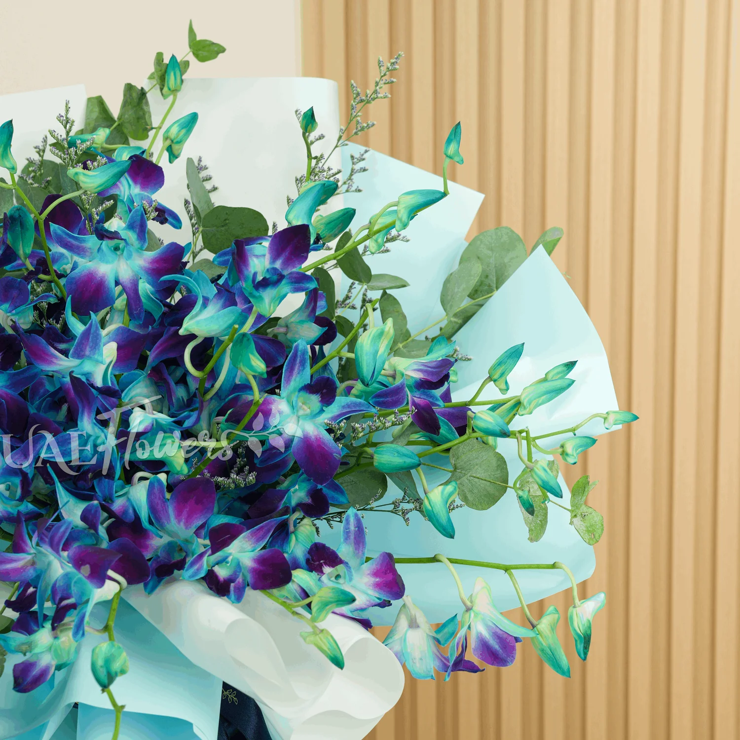 Bouquet of 20 stems of blue orchids with greens and limonium fillers wrapped in paper packing.