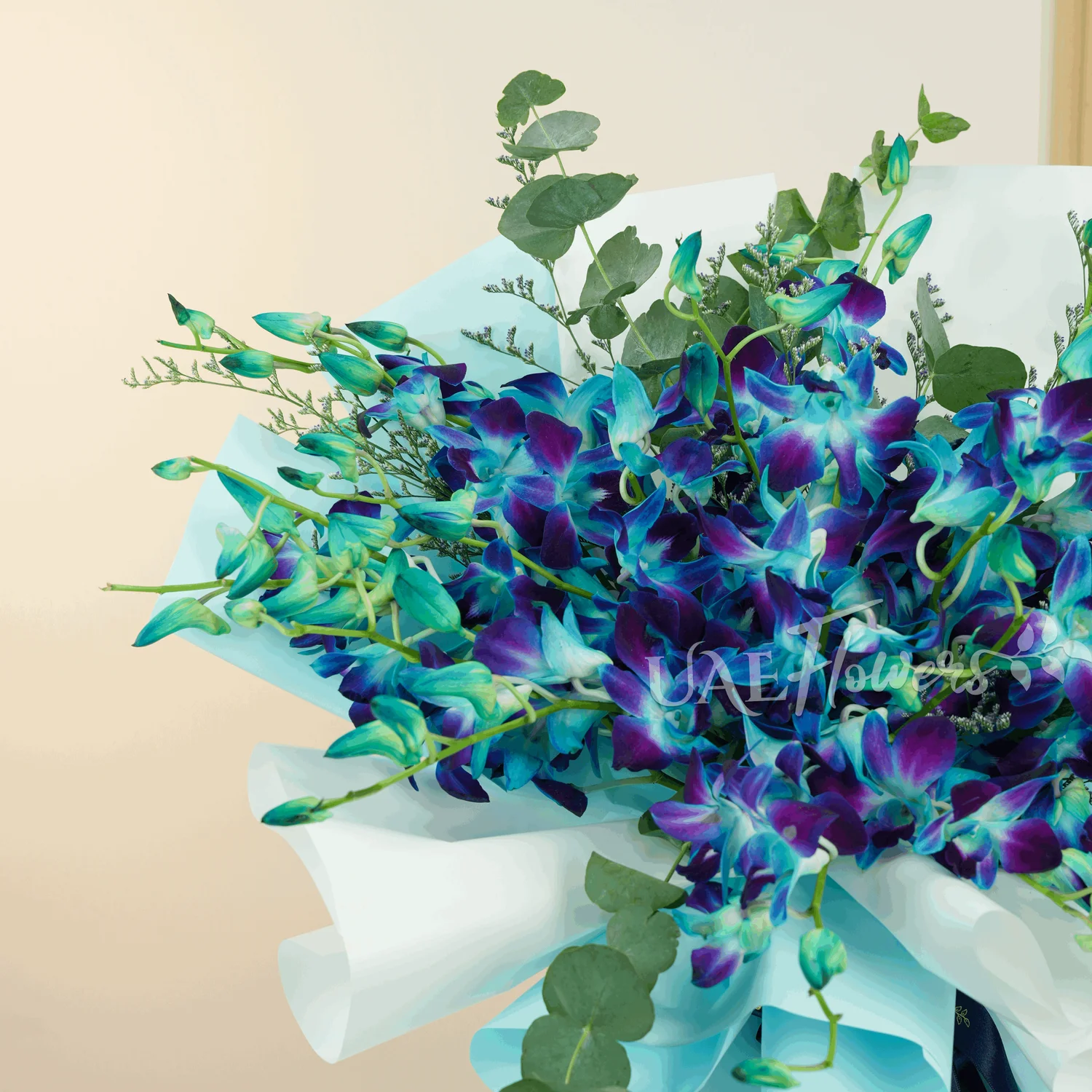 Bouquet of 20 stems of blue orchids with greens and limonium fillers wrapped in paper packing.