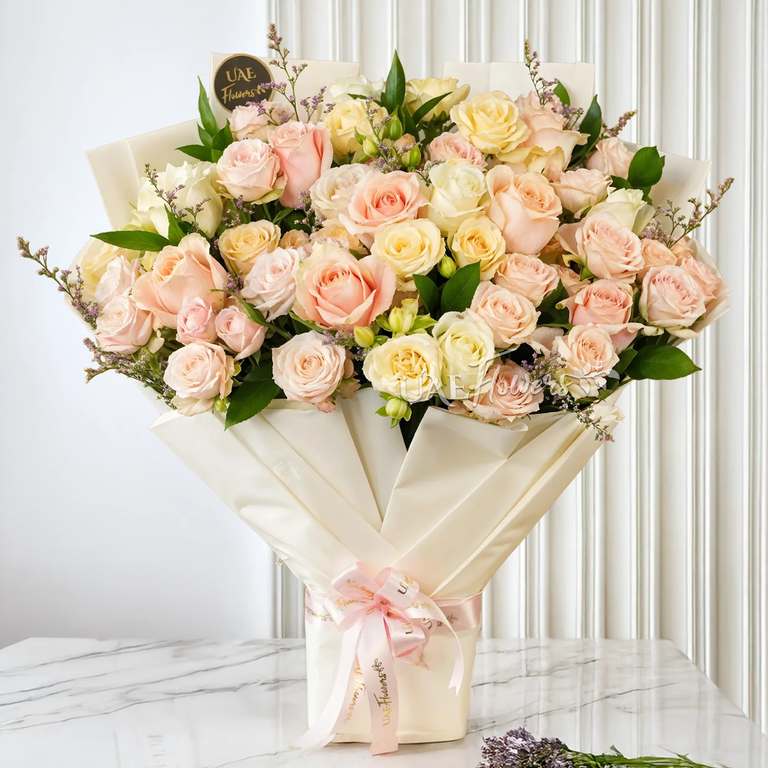 Bouquet of 6 pink spray roses, 6 peach spray roses, 6 pink roses and 6 white roses with limonium & green fillers tied with ribbons.