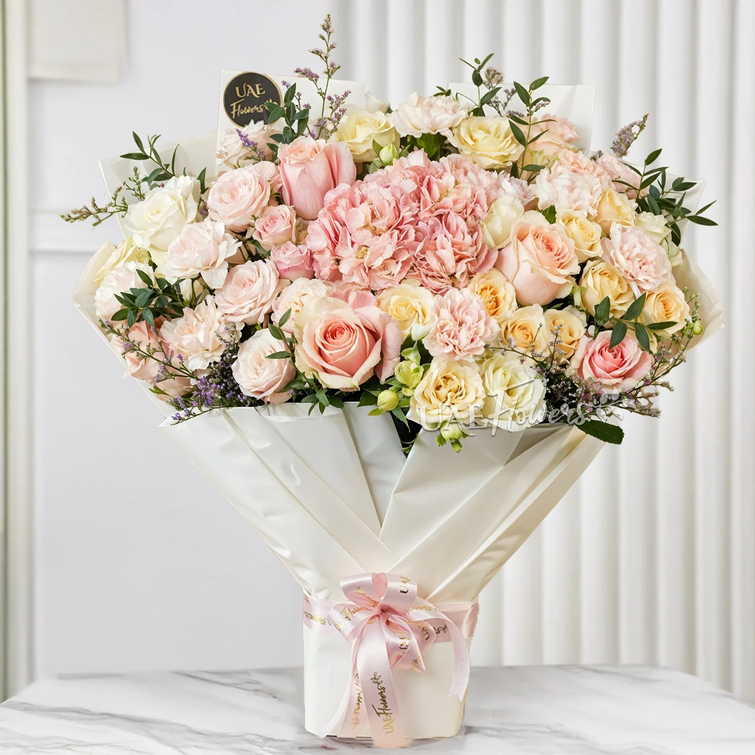Bouquet of 1 pink hydrangea, 3 pink spray roses, 3 peach spray roses, 5 pink carnations and 10 white and pink roses with limonium & green fillers tied with ribbons.
