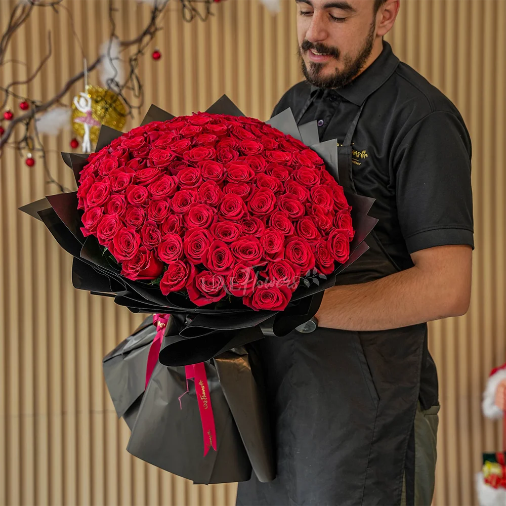 Bouquet of 100 stems of red roses with fillers in black wrapping