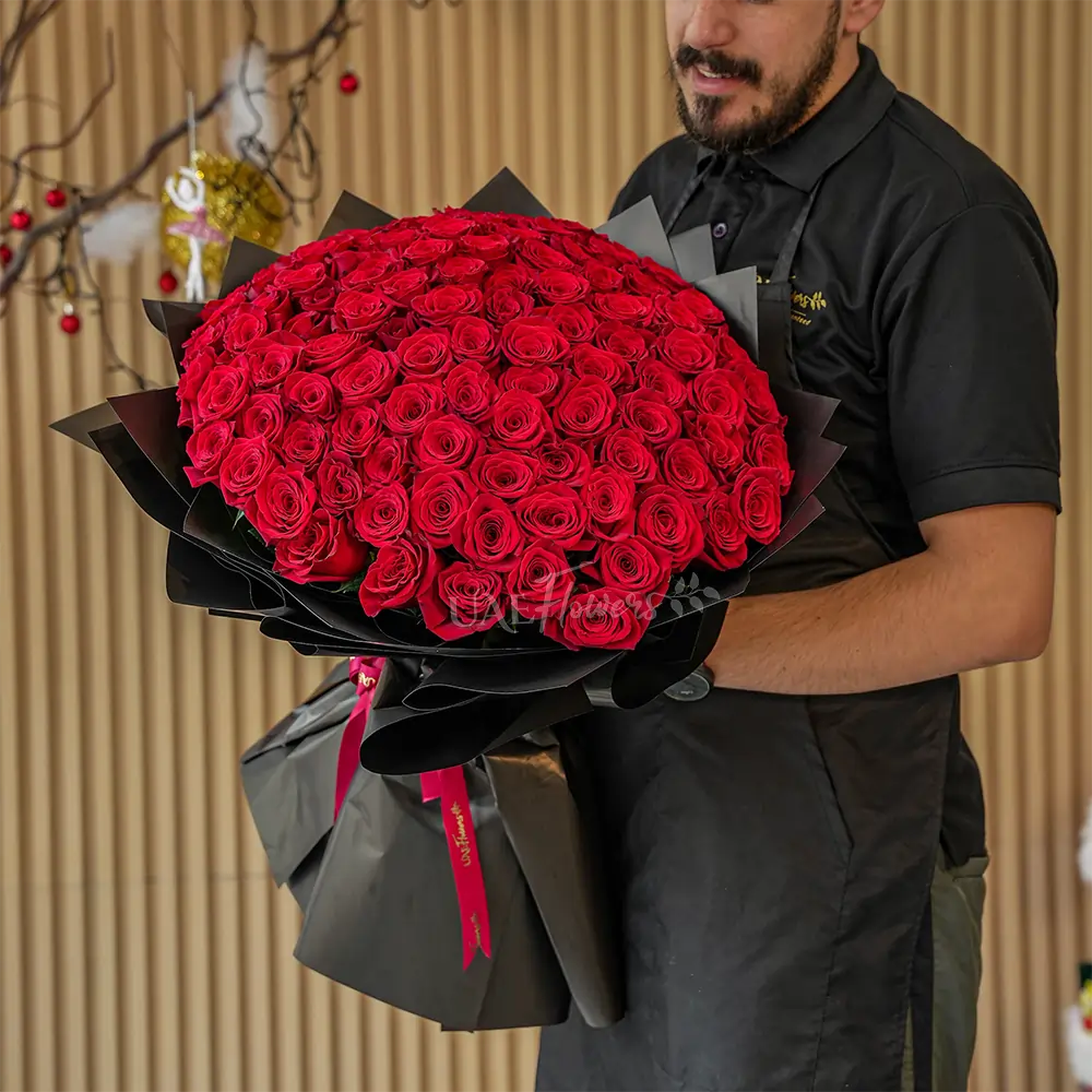Bouquet of 100 stems of red roses with fillers in black wrapping
