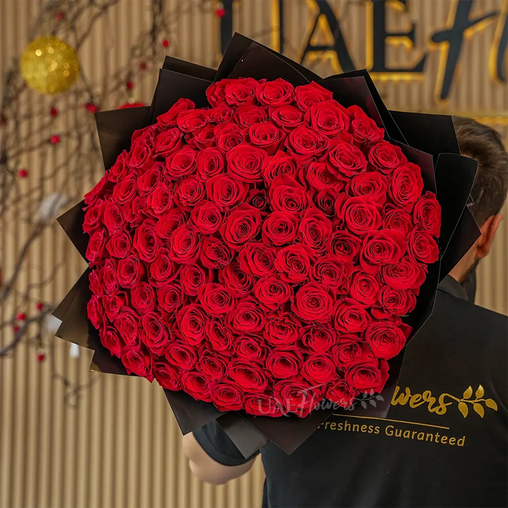 Bouquet of 100 stems of red roses with fillers in black wrapping