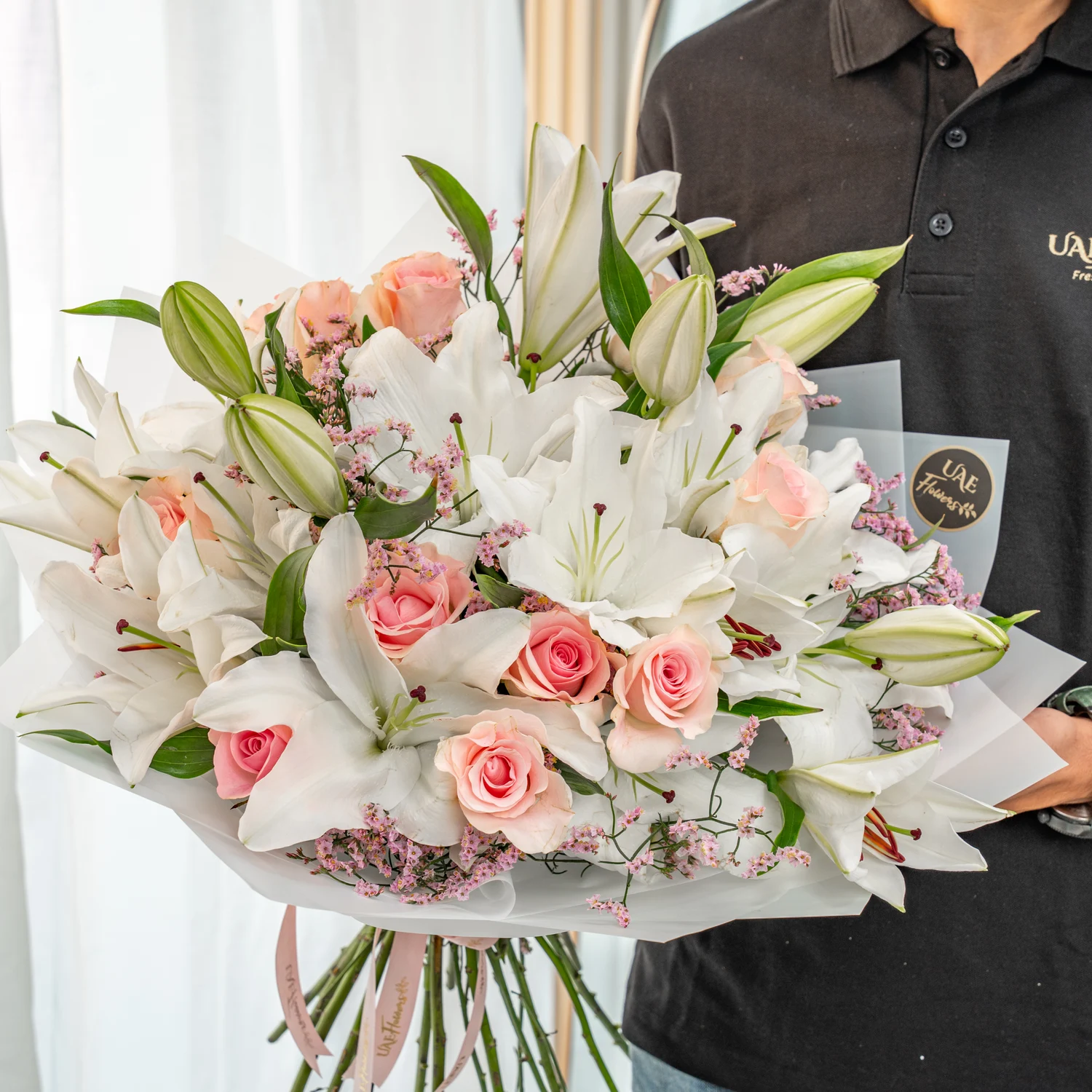 Bouquet of 5 white lilies & 12 pink roses wrapped in white paper packing.