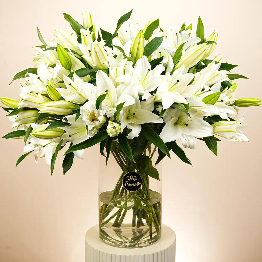 20 white lilies in a clear glass vase.