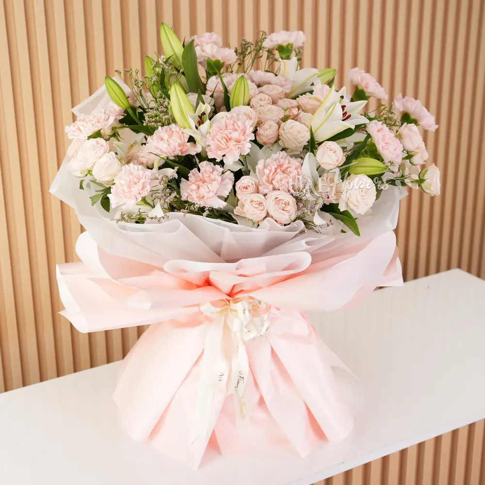 Bouquet of, white lilies, pink carnations, pink spray roses with green fillers wrapped in paper packing and tied with ribbons.