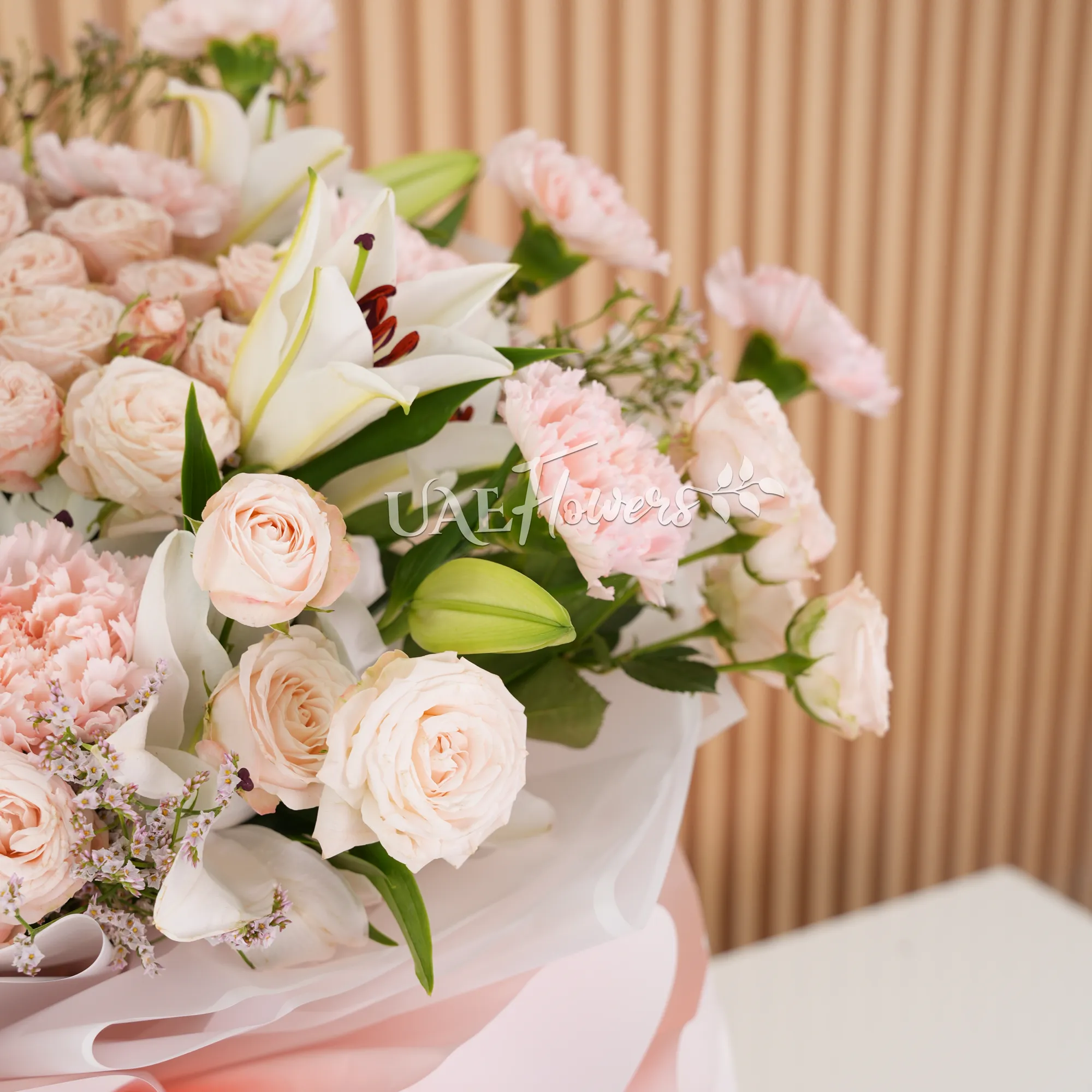 Bouquet of, white lilies, pink carnations, pink spray roses with green fillers wrapped in paper packing and tied with ribbons.