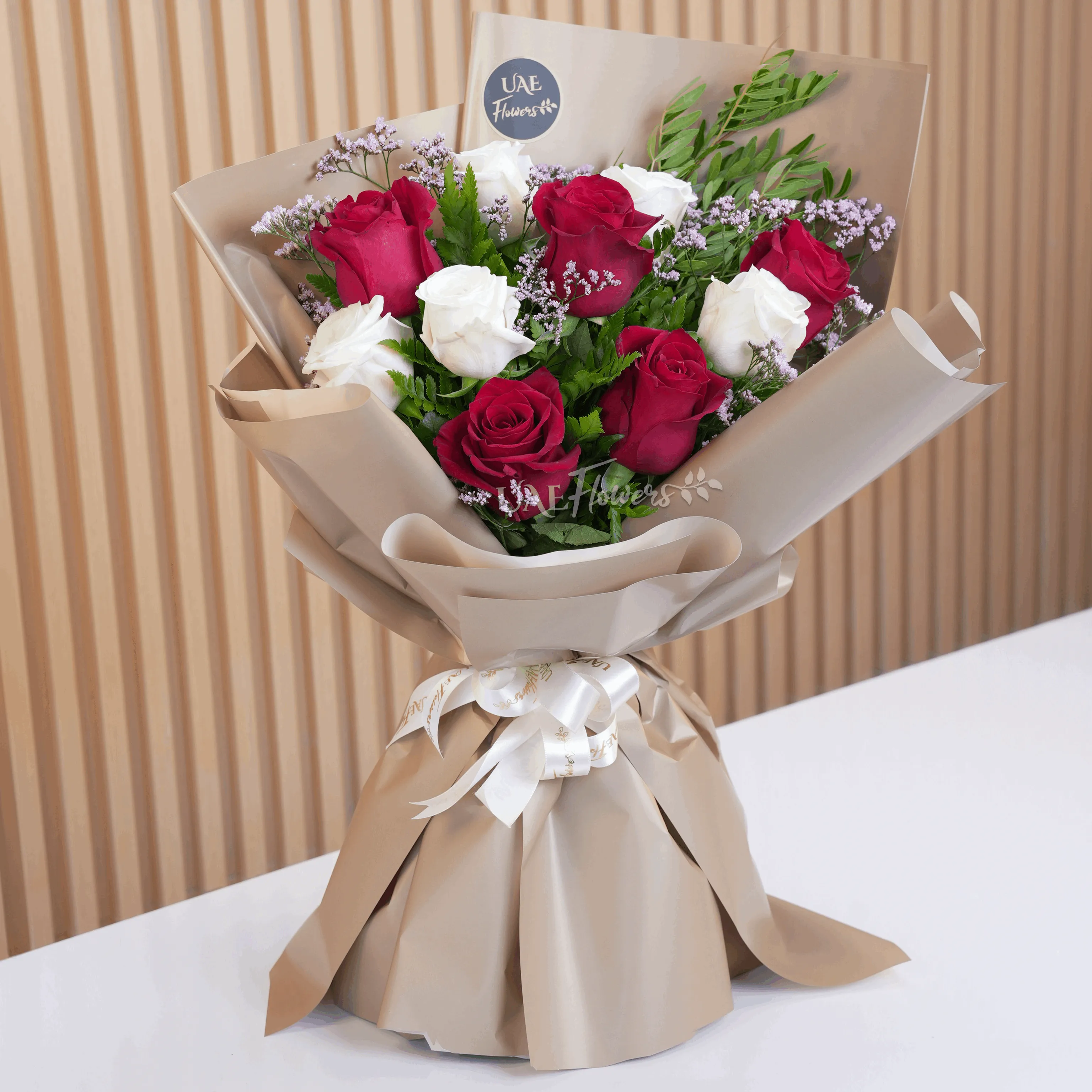 Bouquet of 10 red and white roses with green fillers in wrapping paper and tied with ribbons.