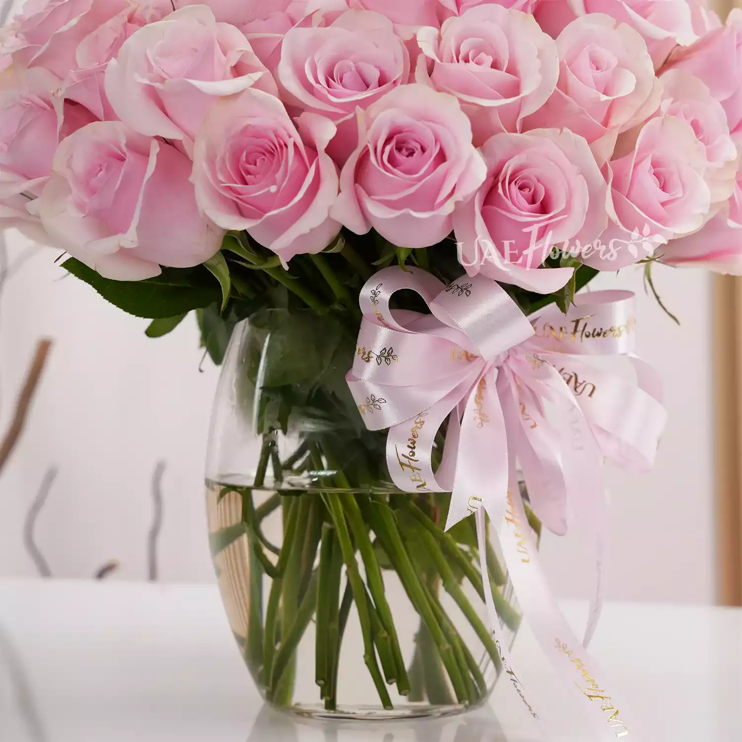 Separate vase arrangements of 50 red roses with green fillers and 50 pink roses with green fillers.