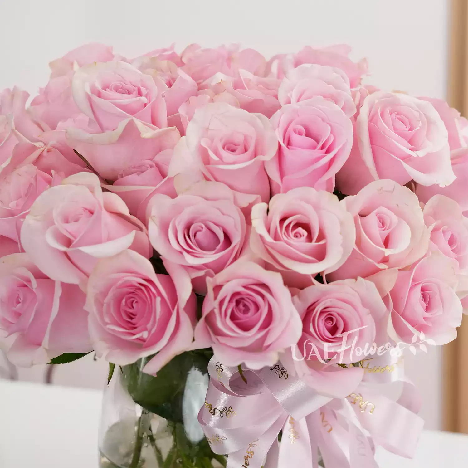 Separate vase arrangements of 50 red roses with green fillers and 50 pink roses with green fillers.