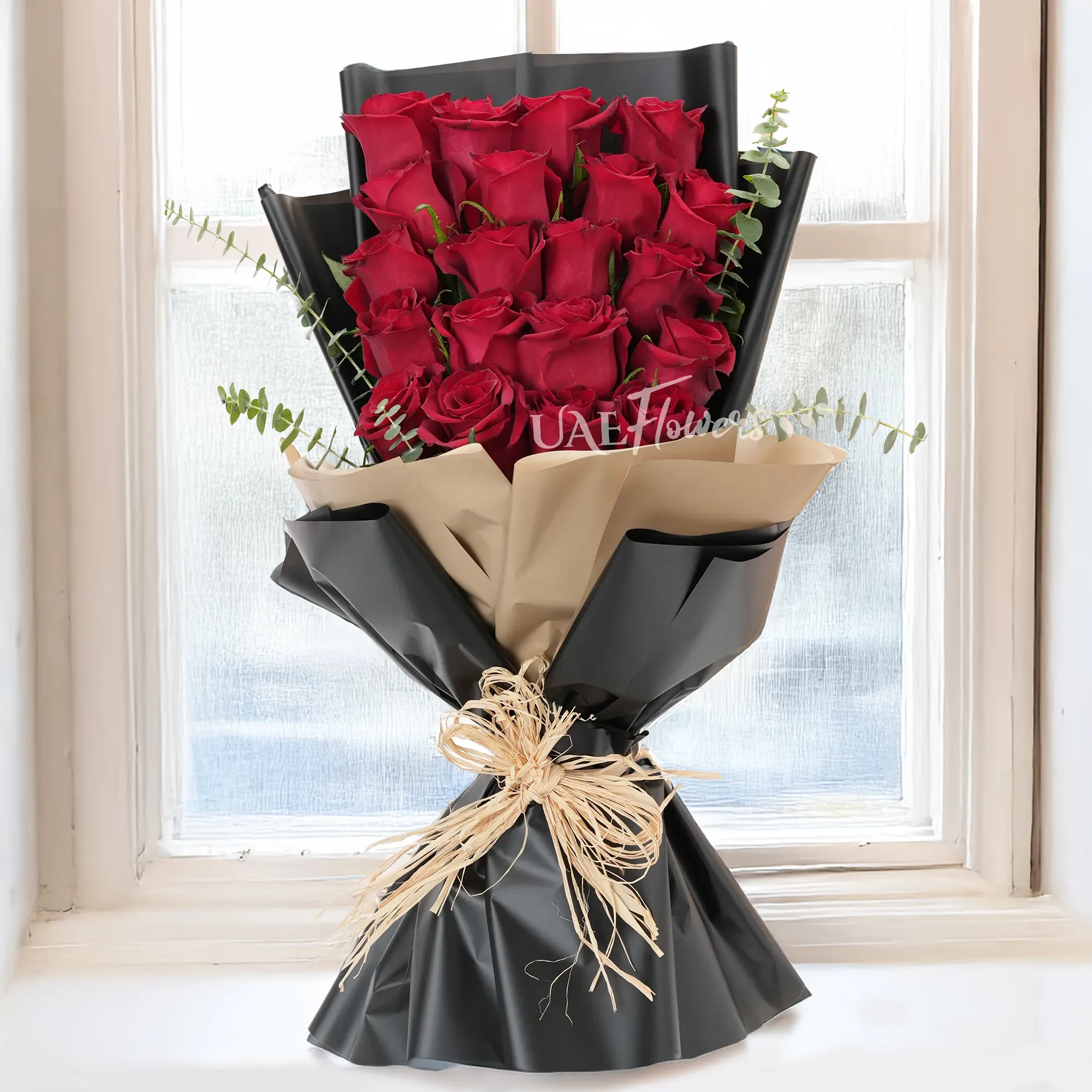 Bouquet of 20 red roses with green fillers in paper packing.