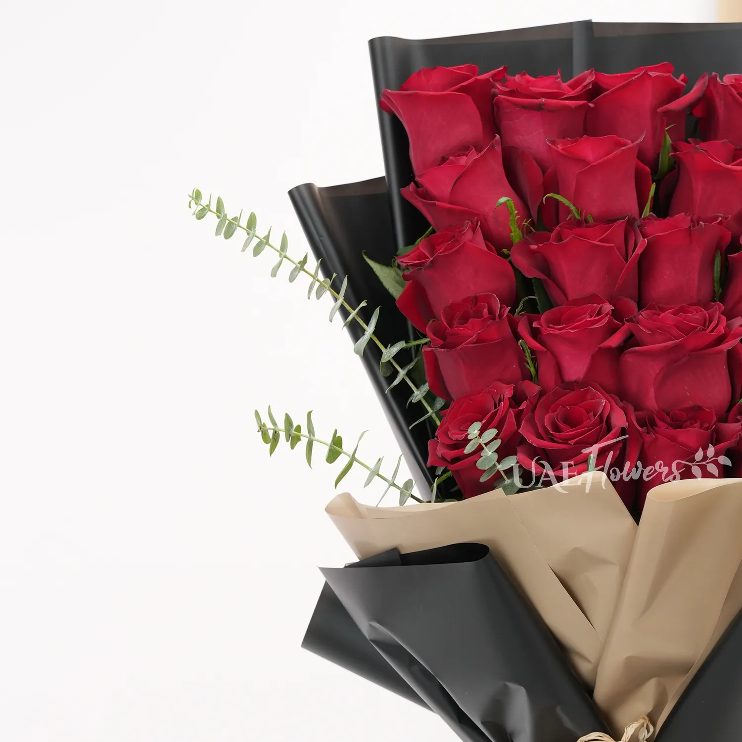 Bouquet of 20 red roses with green fillers in paper packing.