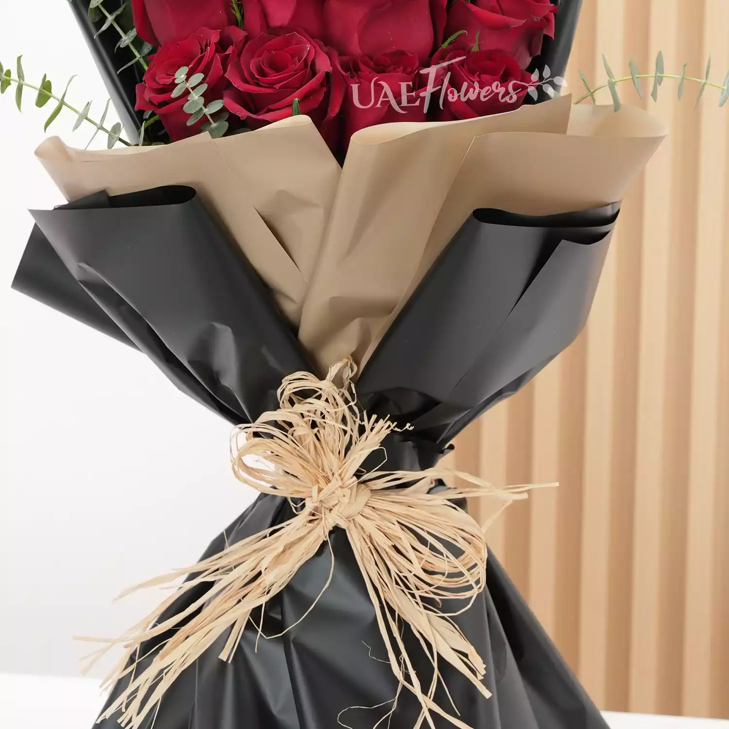 Bouquet of 20 red roses with green fillers in paper packing.