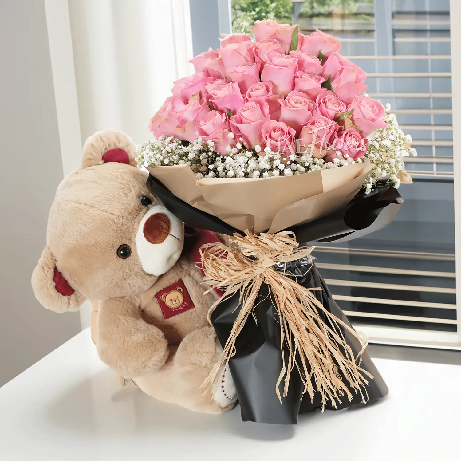 Bouquet of 20 pink roses with baby's breath fillers in paper packing with medium size brown teddy bear
