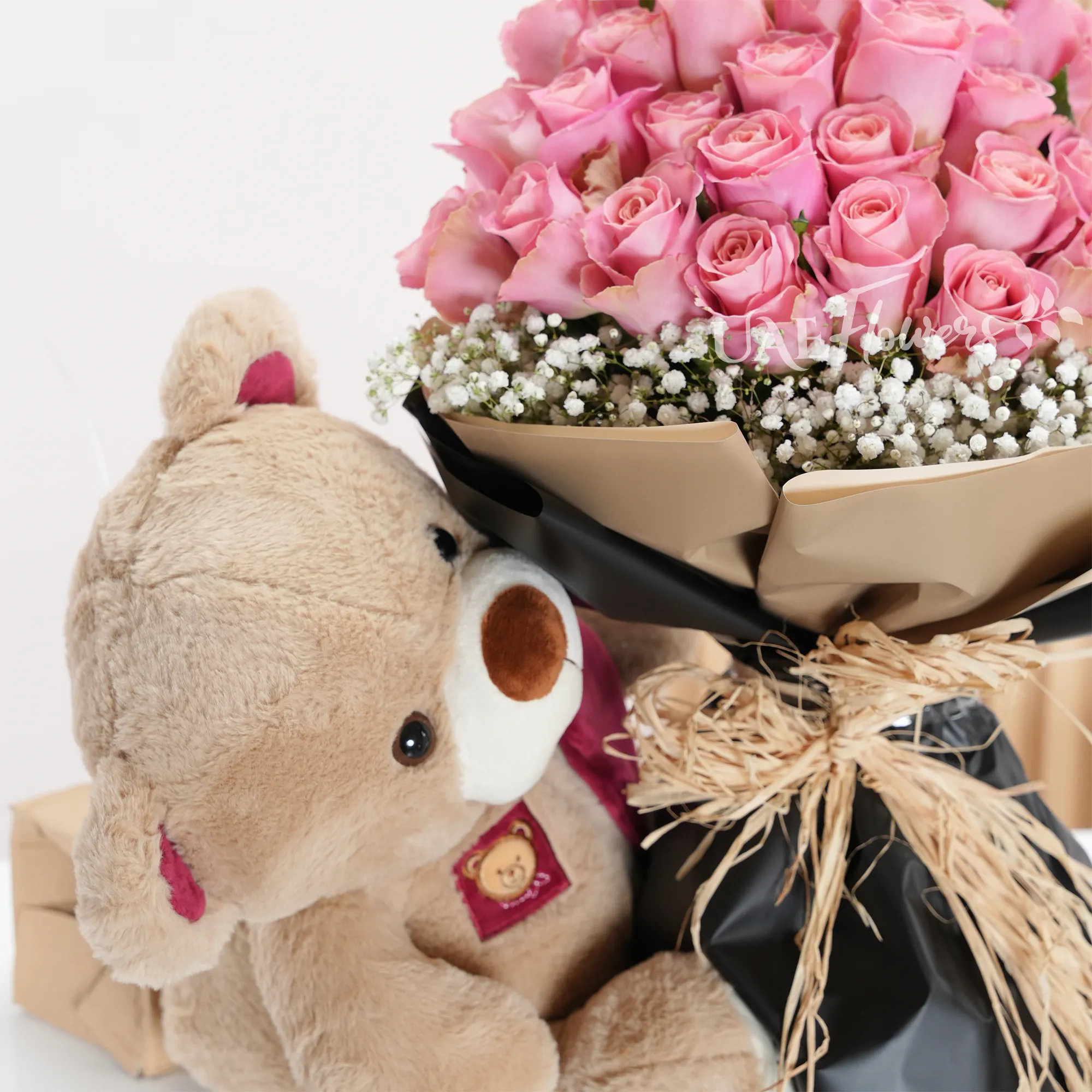 Bouquet of 20 pink roses with baby's breath fillers in paper packing with medium size brown teddy bear