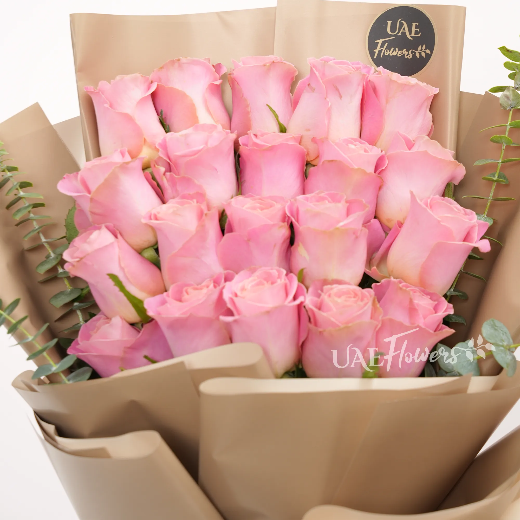 Bouquet of 20 pink roses with green fillers in paper packing tied with brown ribbons.