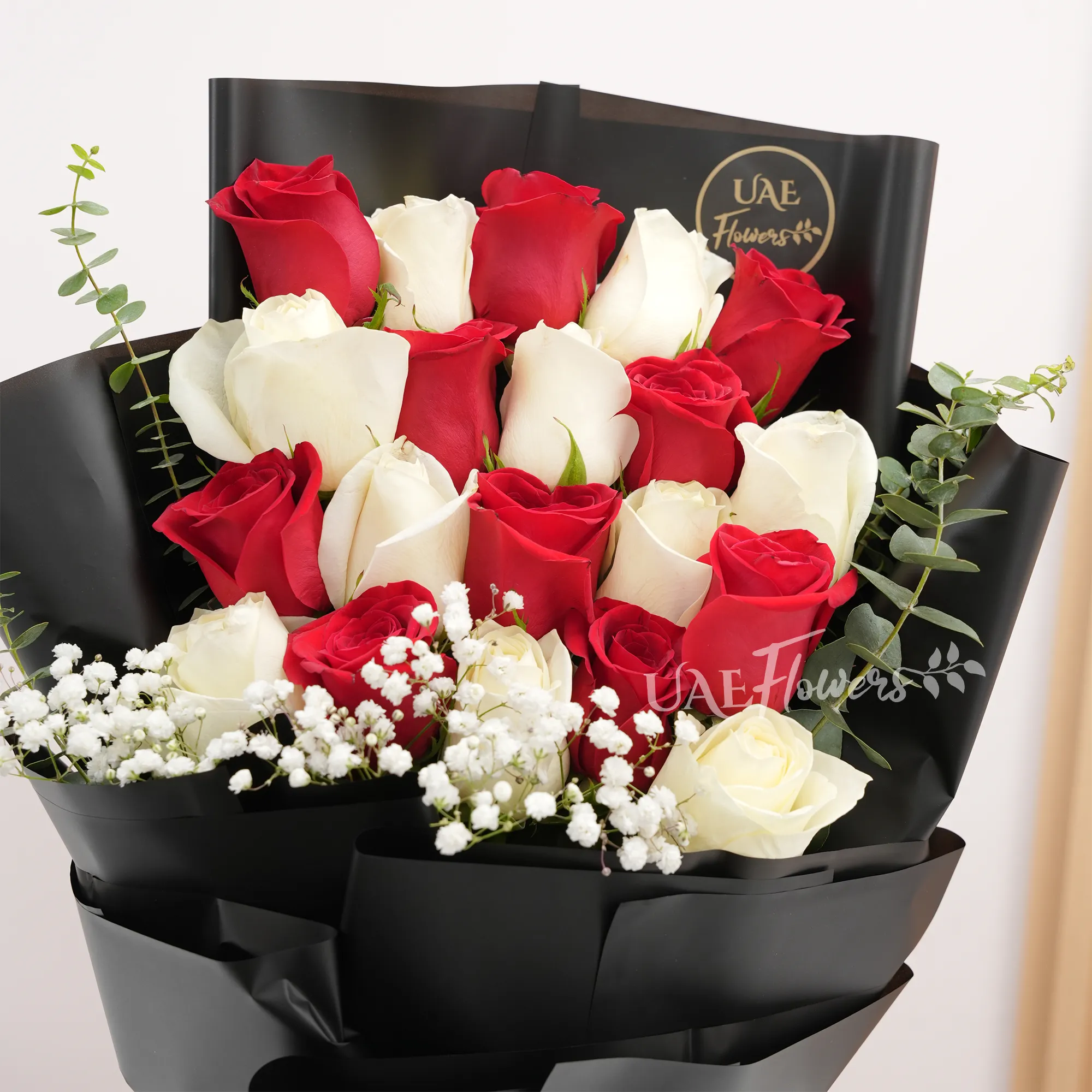 Bouquet of 20 red and white roses with baby's breath fillers in black wrapping paper tied with white ribbons.