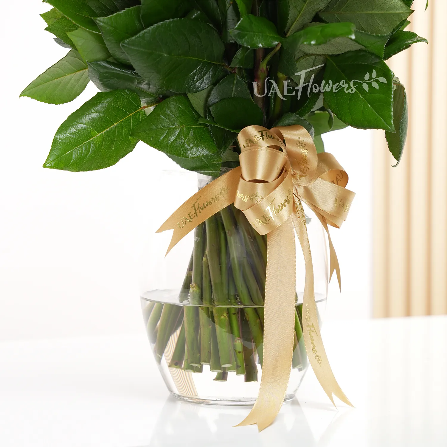 A vase arrangement of 50 red roses with green fillers and tied with golden ribbons.