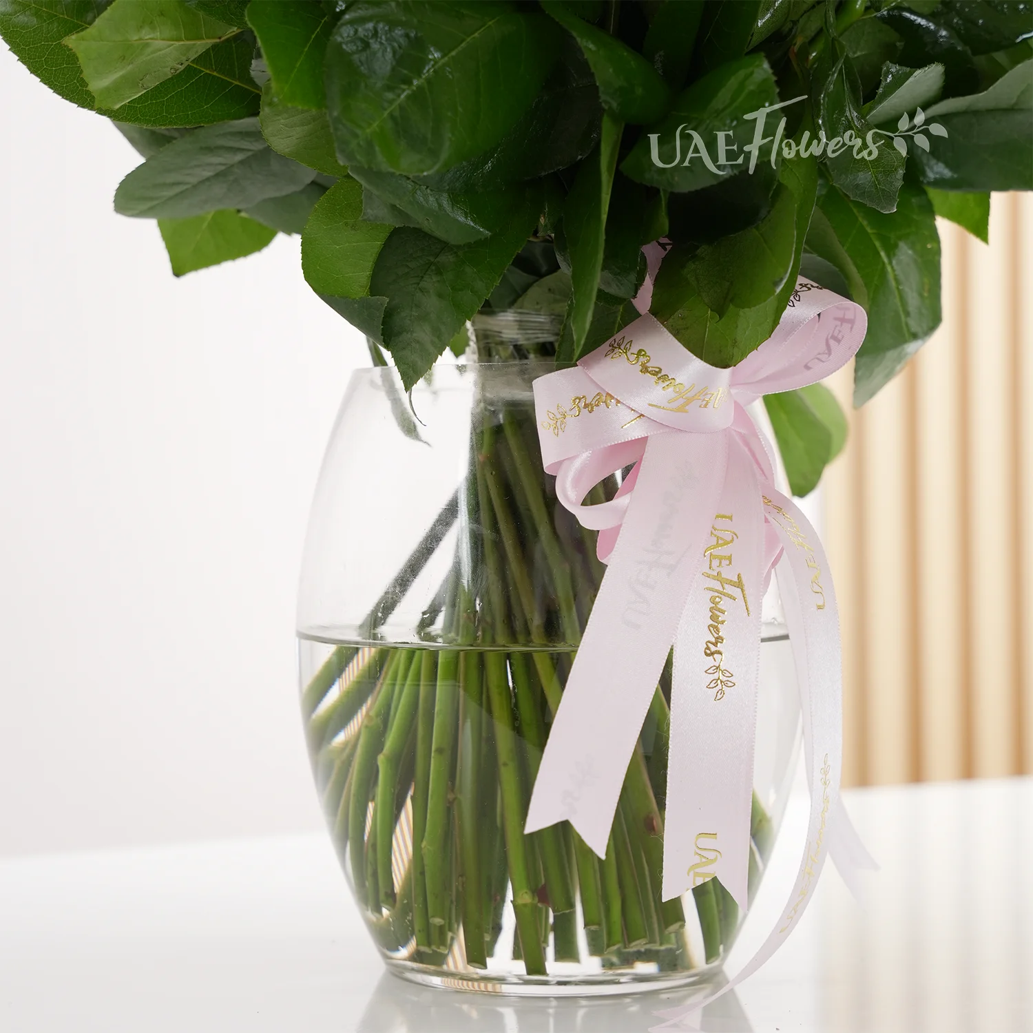 A vase arrangement of 40 pink roses with green fillers tied with pink ribbons.