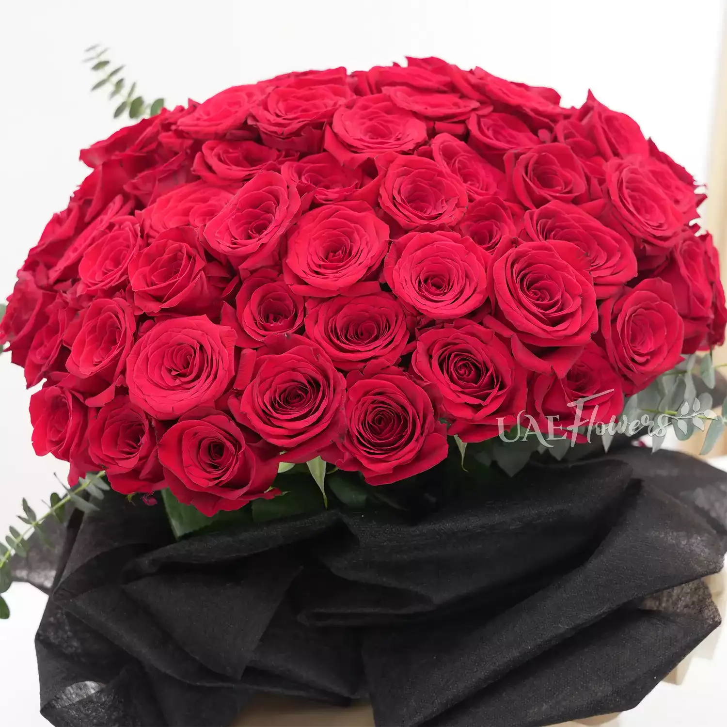 Bouquet of 40 red roses with eucalyptus leaf in black and brown paper packing tied with brown ribbons.