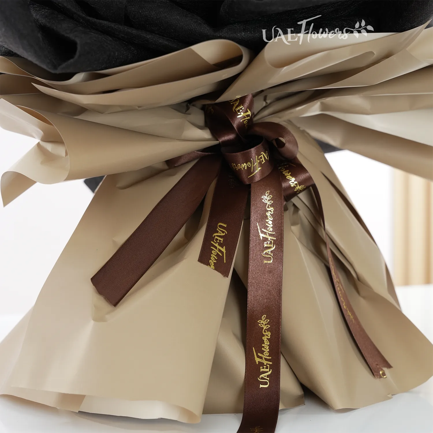 Bouquet of 40 red roses with eucalyptus leaf in black and brown paper packing tied with brown ribbons.