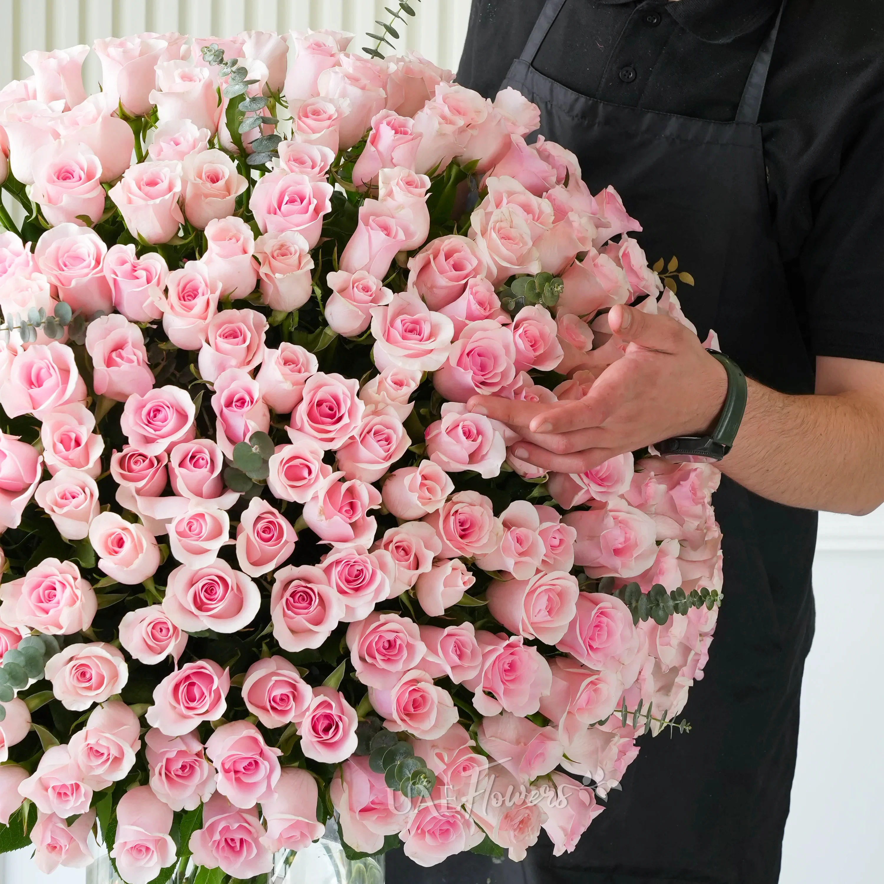 A vase with 200 pink roses with green fillers.