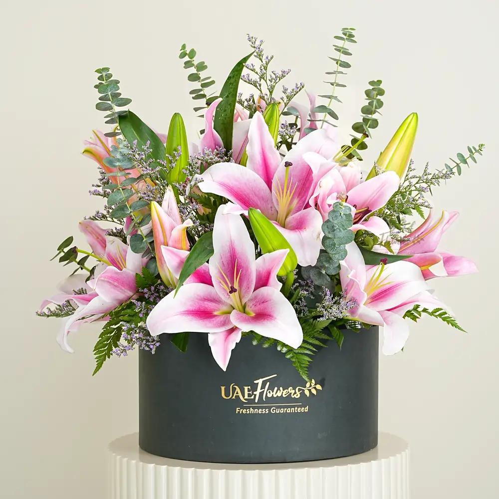 5 pink lilies with eucalyptus leaf and limonium fillers in a black box.